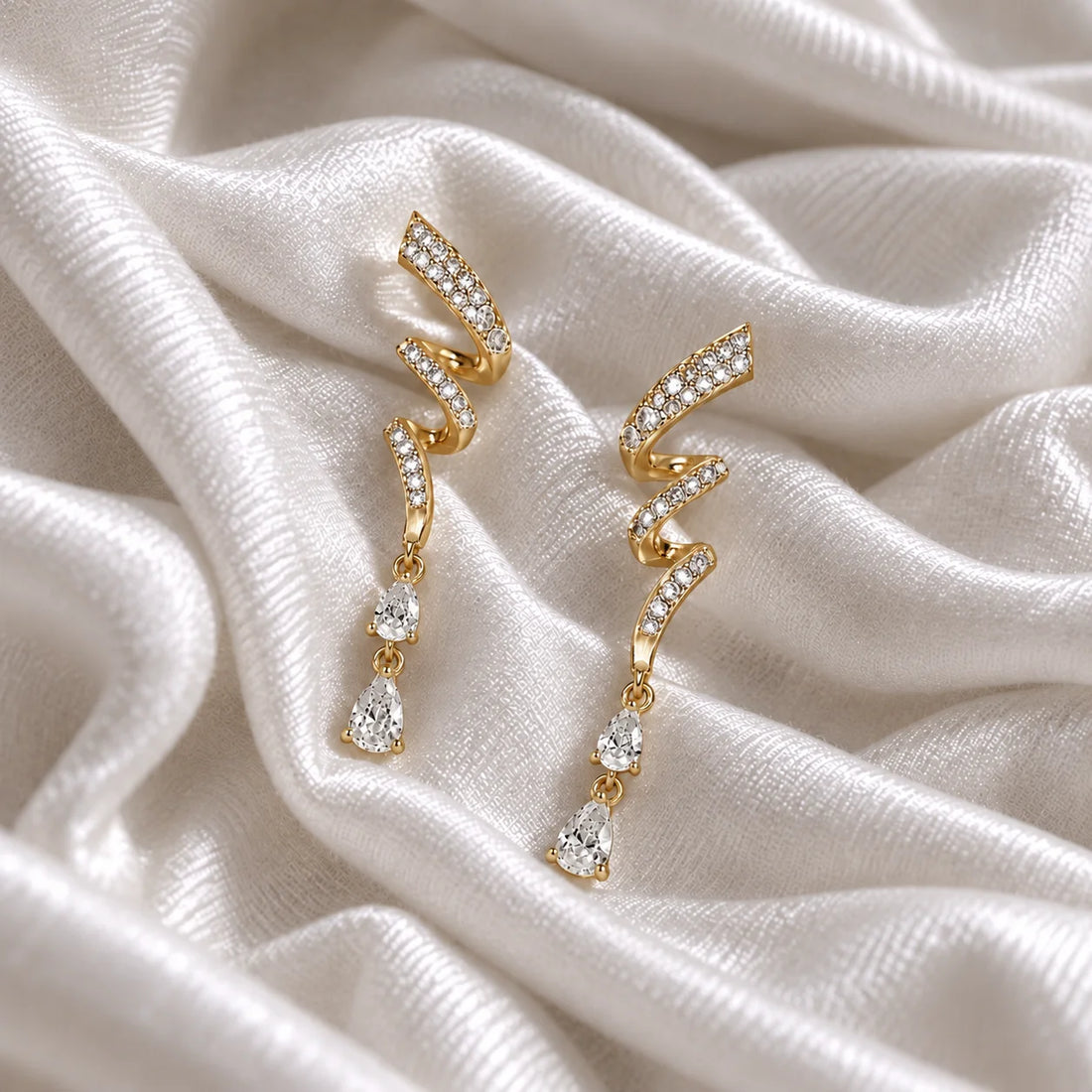 Diamond_drop_earrings_in_gold_plated_silver_with_twisted_design_lab_grown_diamonds_at_front_angle_view_on_soft_fabric_background