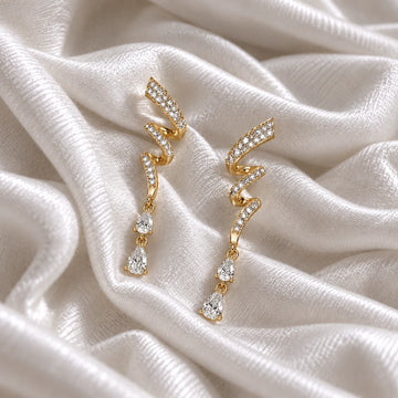 Diamond_drop_earrings_in_gold_plated_silver_with_twisted_design_lab_grown_diamonds_at_front_angle_view_on_soft_fabric_background