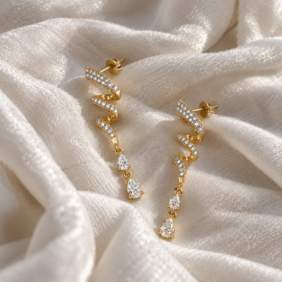 Diamond_drop_earrings_in_gold_plated_silver_with_twisted_design_lab_grown_diamonds_at_side_angle_view_on_soft_fabric_background