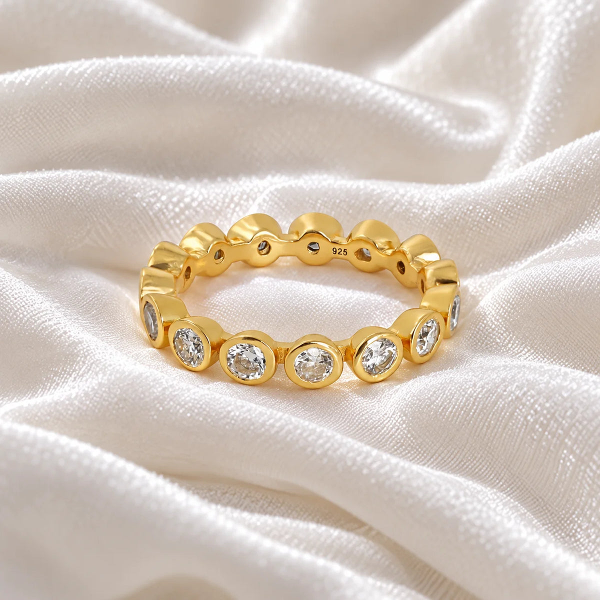 Diamond_eternity_ring_in_gold_plated_silver_with_lab_grown_diamonds_at_front_angle_view_on_soft_fabric_background