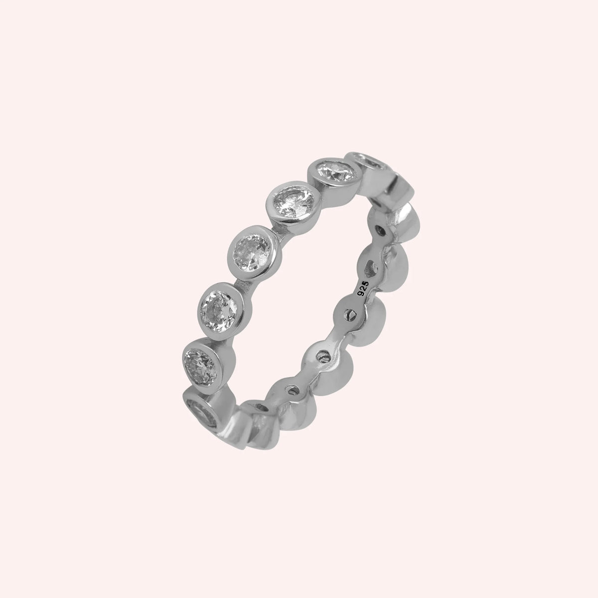 Diamond_eternity_ring_in_sterling_silver_with_lab_grown_diamonds_at_slight_angle_view_on_solid_pink_background