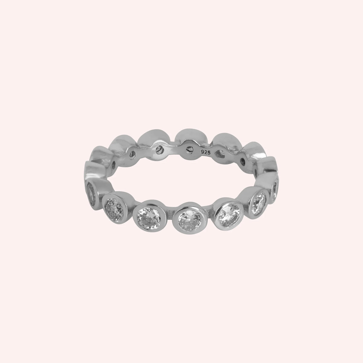 Diamond_eternity_ring_in_sterling_silver_with_lab_grown_diamonds_at_front_angle_view_on_solid_pink_background