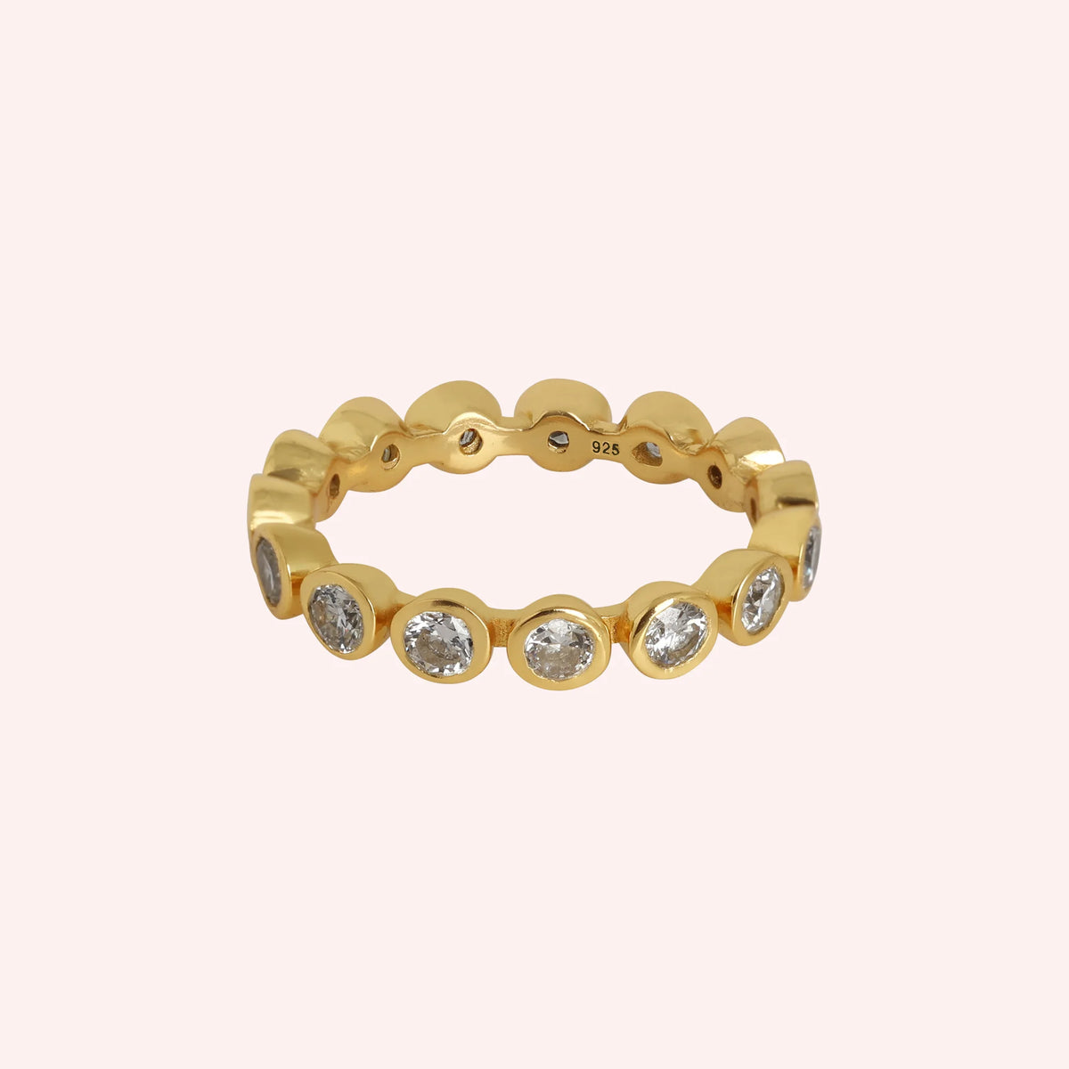 Diamond_eternity_ring_in_gold_plated_silver_with_lab_grown_diamonds_at_front_angle_view_on_solid_pink_background