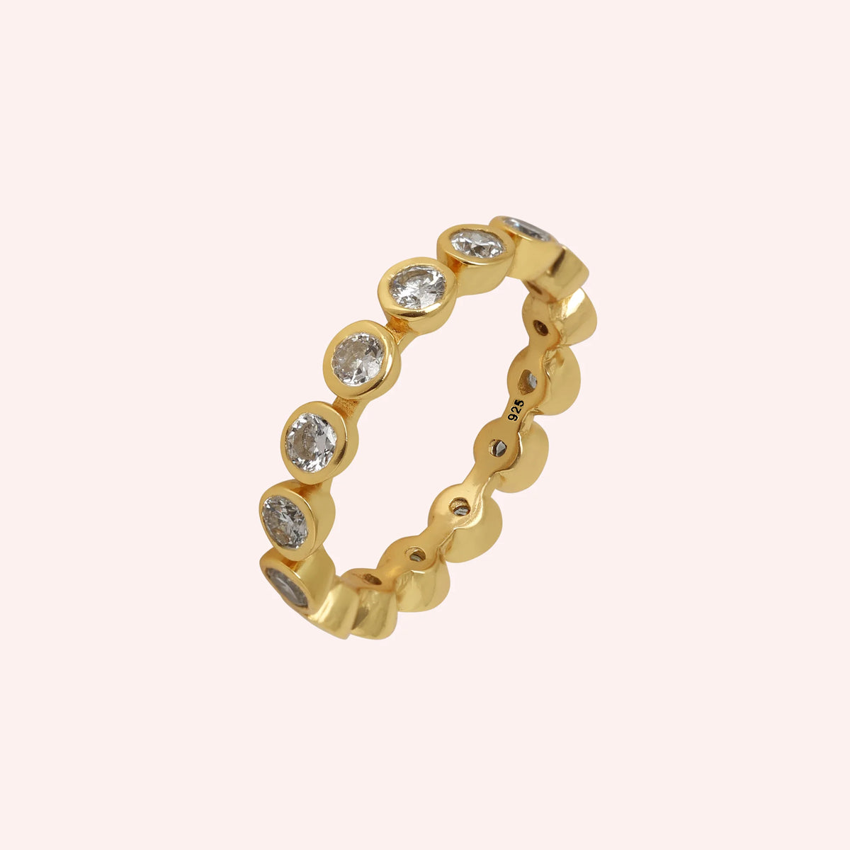 Diamond_eternity_ring_in_gold_plated_silver_with_lab_grown_diamonds_at_slight_angle_view_on_solid_pink_background