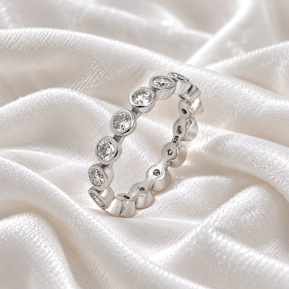 Diamond_eternity_ring_in_sterling_silver_with_lab_grown_diamonds_at_slight_angle_view_on_soft_fabric_background