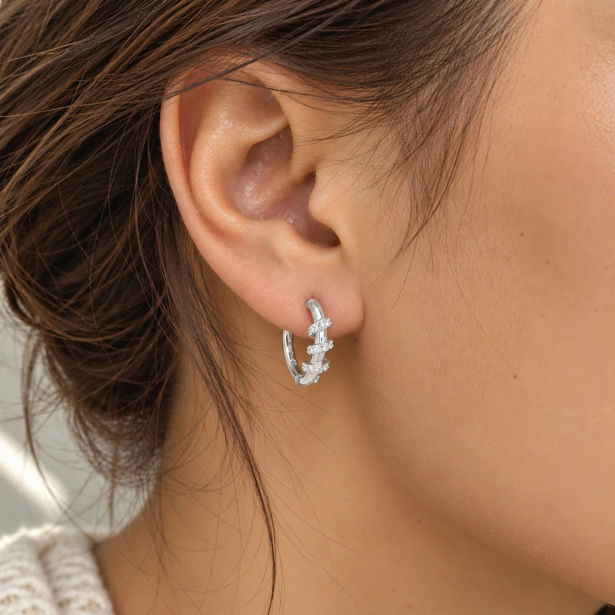 Diamond_hoop_earrings_in_sterling_silver_with_a_twisted_design_worn_by_a_model