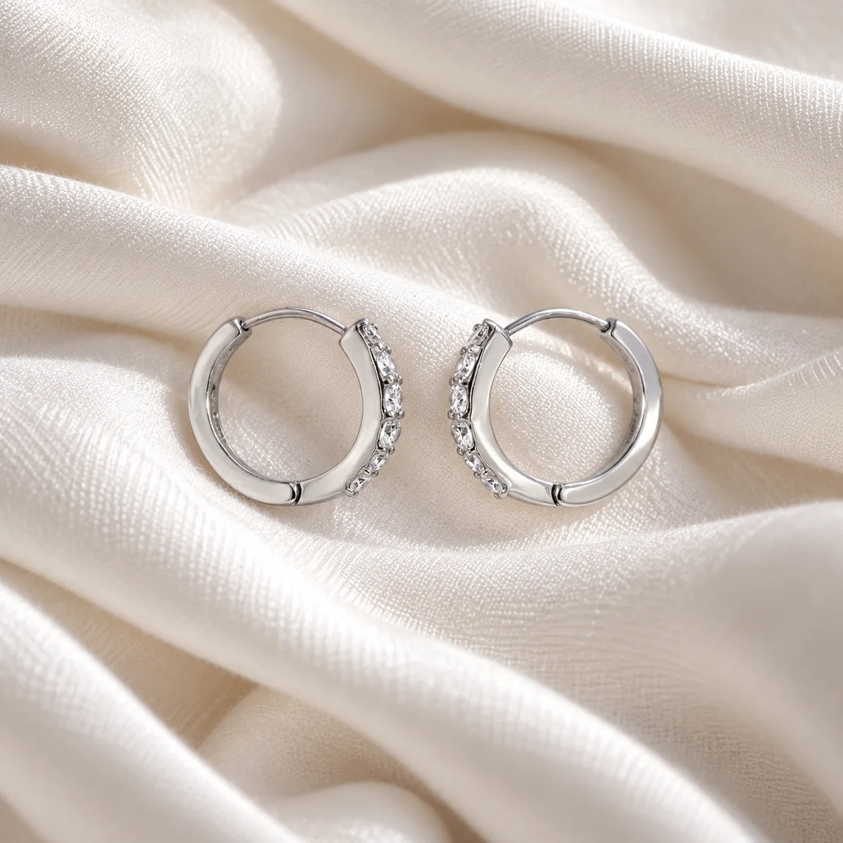 Diamond_hoop_earrings_in_sterling_silver_with_lab_grown_diamonds_at_slight_angle_view_on_soft_fabric_background