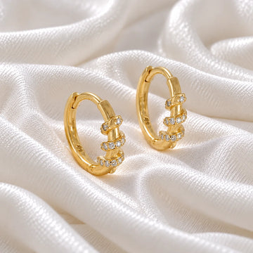 Diamond_hoop_earrings_in_gold_plated_silver_with_a_twisted_design_band_at_front_angle_view_on_soft_fabric_background