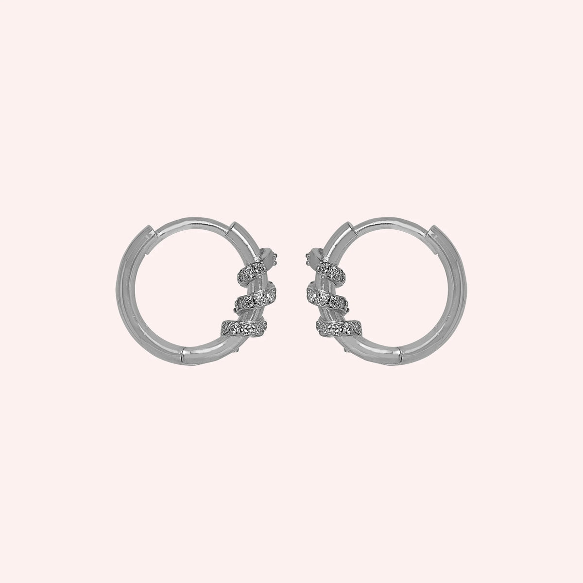 Diamond_hoop_earrings_in_sterling_silver_with_a_twisted_design_band_at_side_angle_view_on_solid_pink_background