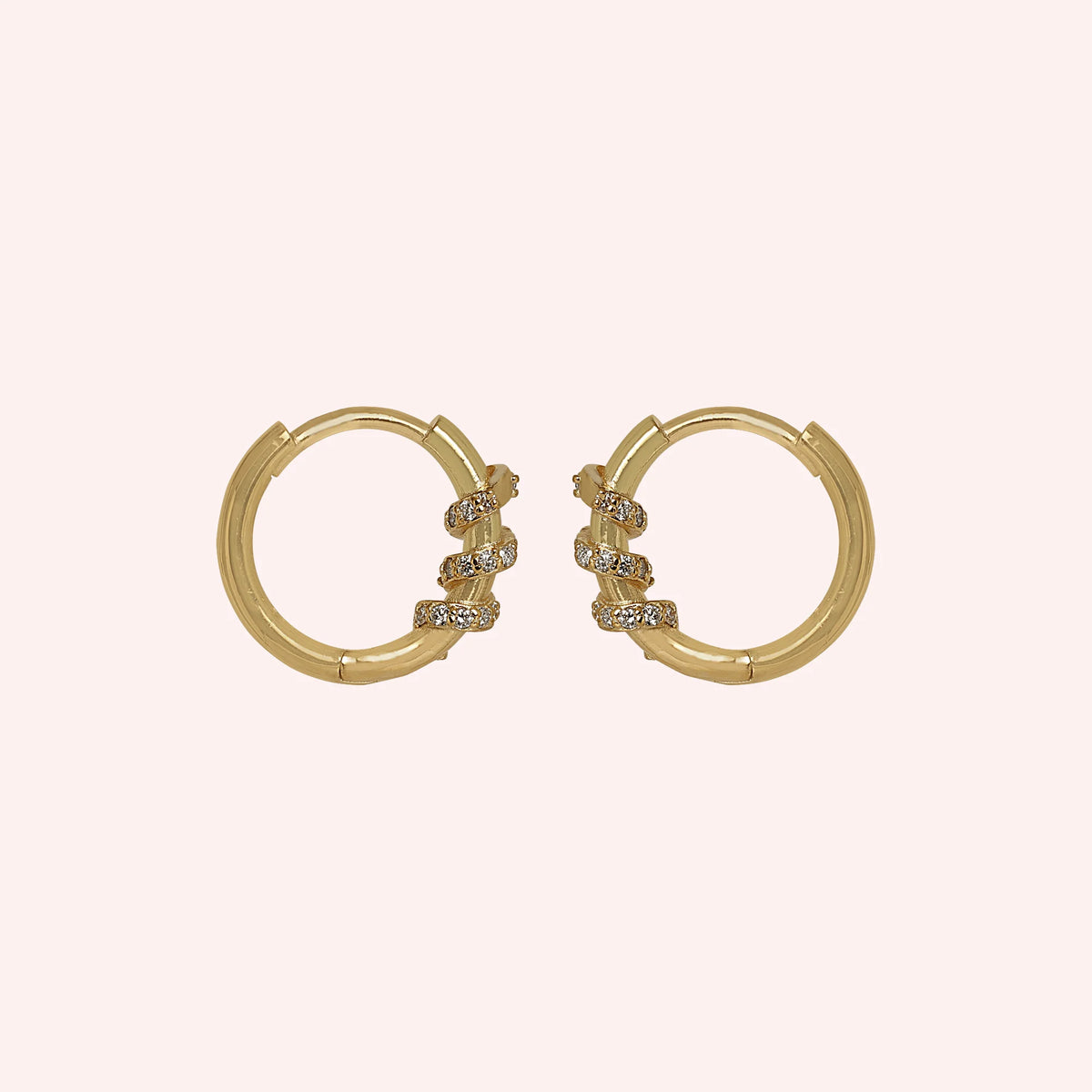 Diamond_hoop_earrings_in_gold_plated_silver_with_a_twisted_design_band_at_side_angle_view_on_solid_pink_background