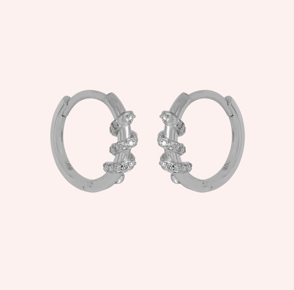 Diamond_hoop_earrings_in_sterling_silver_with_a_twisted_design_band_at_front_angle_view_on_solid_pink_background