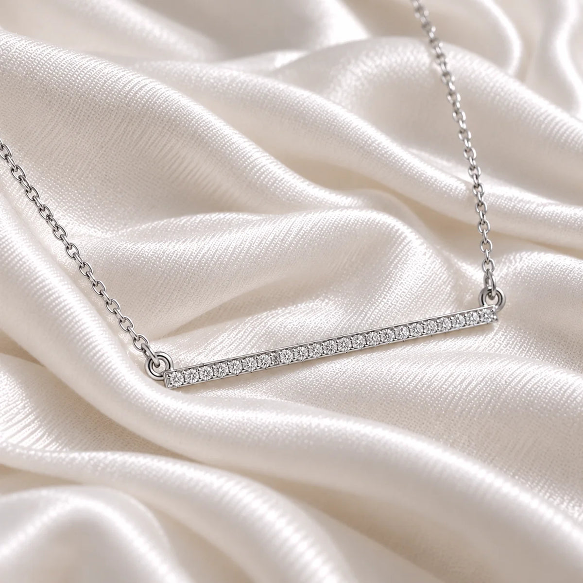 Diamond_necklace_in_sterling_silver_in_a_bar_design_at_side_angle_view_on_soft_fabric_background