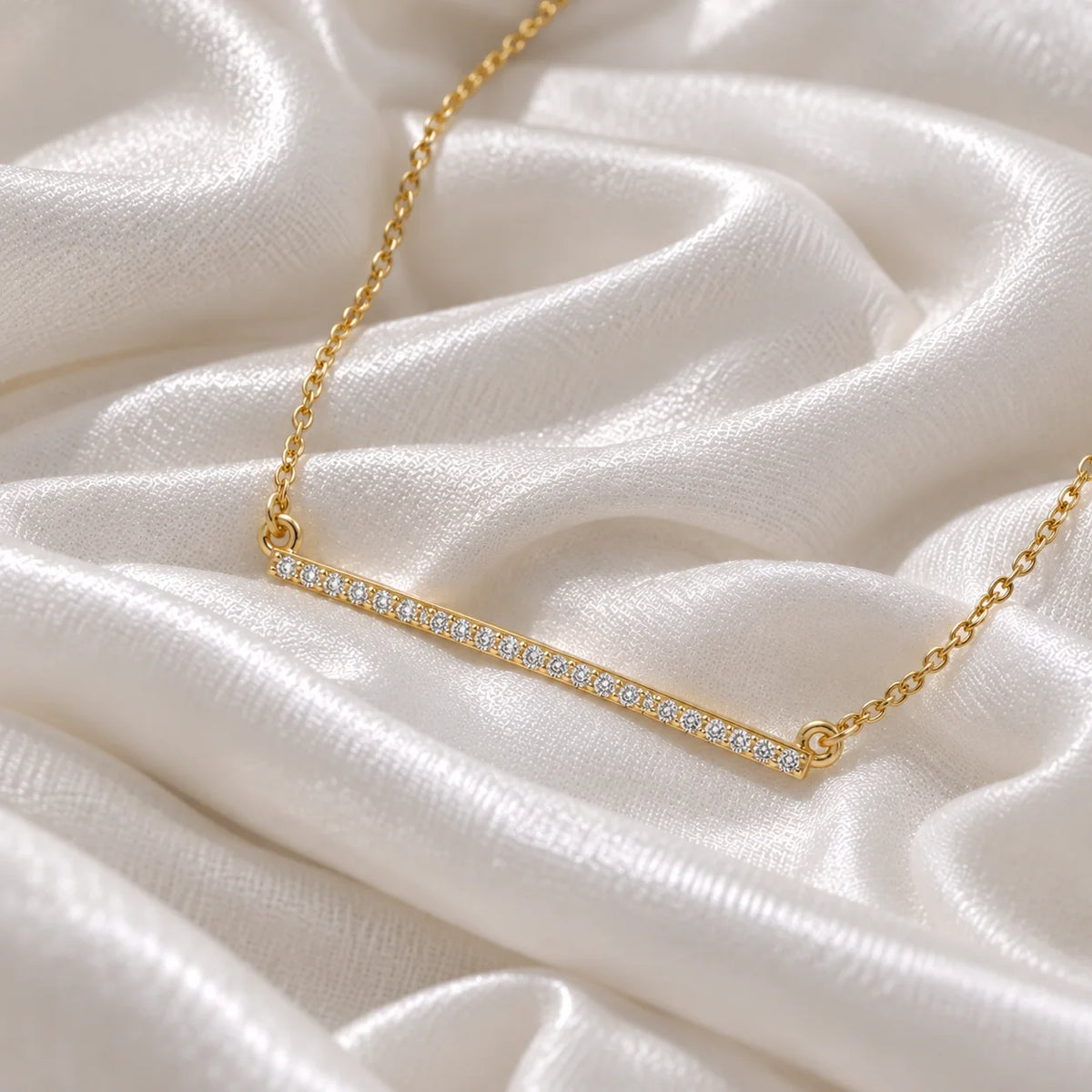 Diamond_necklace_in_gold_plated_silver_in_a_bar_design_at_side_angle_view_on_soft_fabric_background