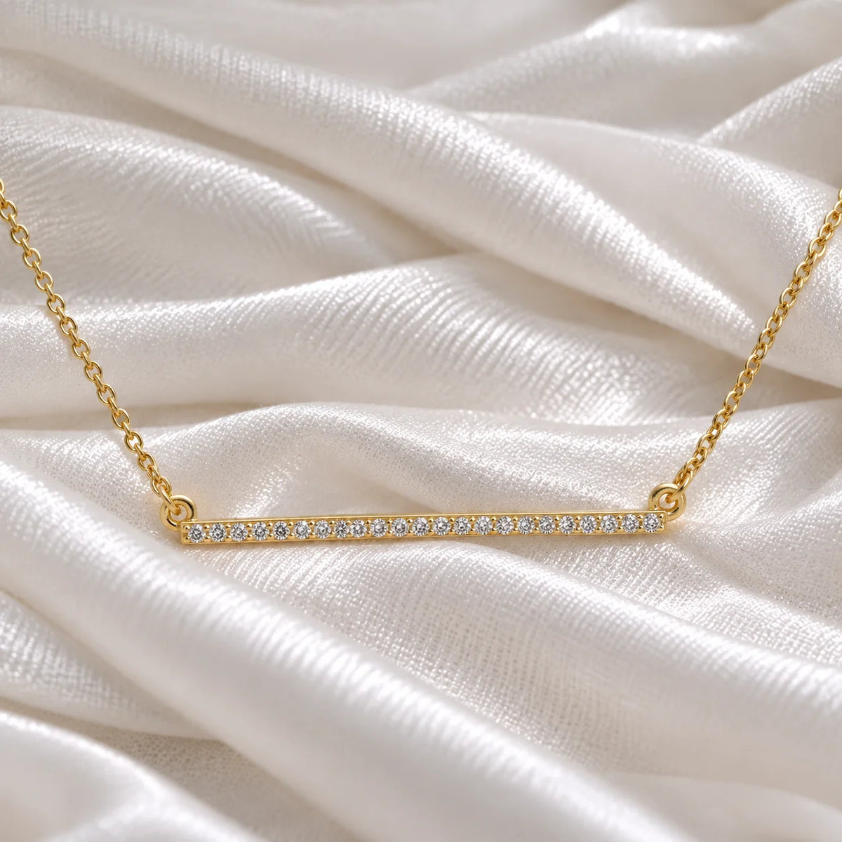 Diamond_necklace_in_gold_plated_silver_in_a_bar_design_at_front_angle_view_on_soft_fabric_background