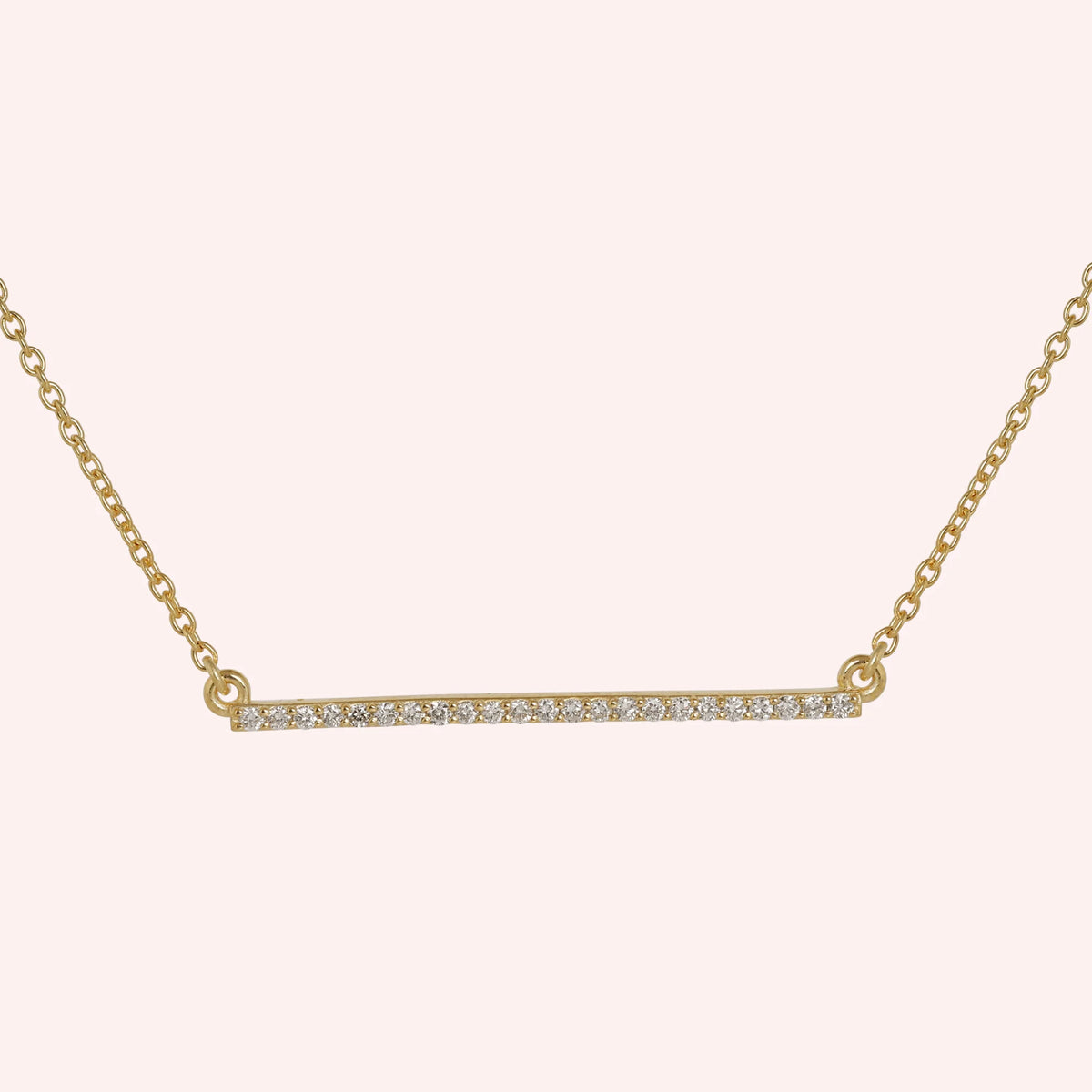 Diamond_necklace_in_gold_plated_silver_in_a_bar_design_at_front_angle_view_on_solid_pink_background