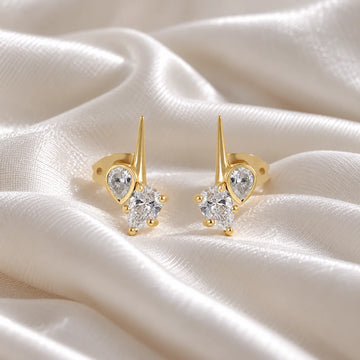 Diamond_stud_earrings_in_gold_plated_silver_with_teardrop_shaped_diamonds_at_front_angle_view_on_soft_fabric_background