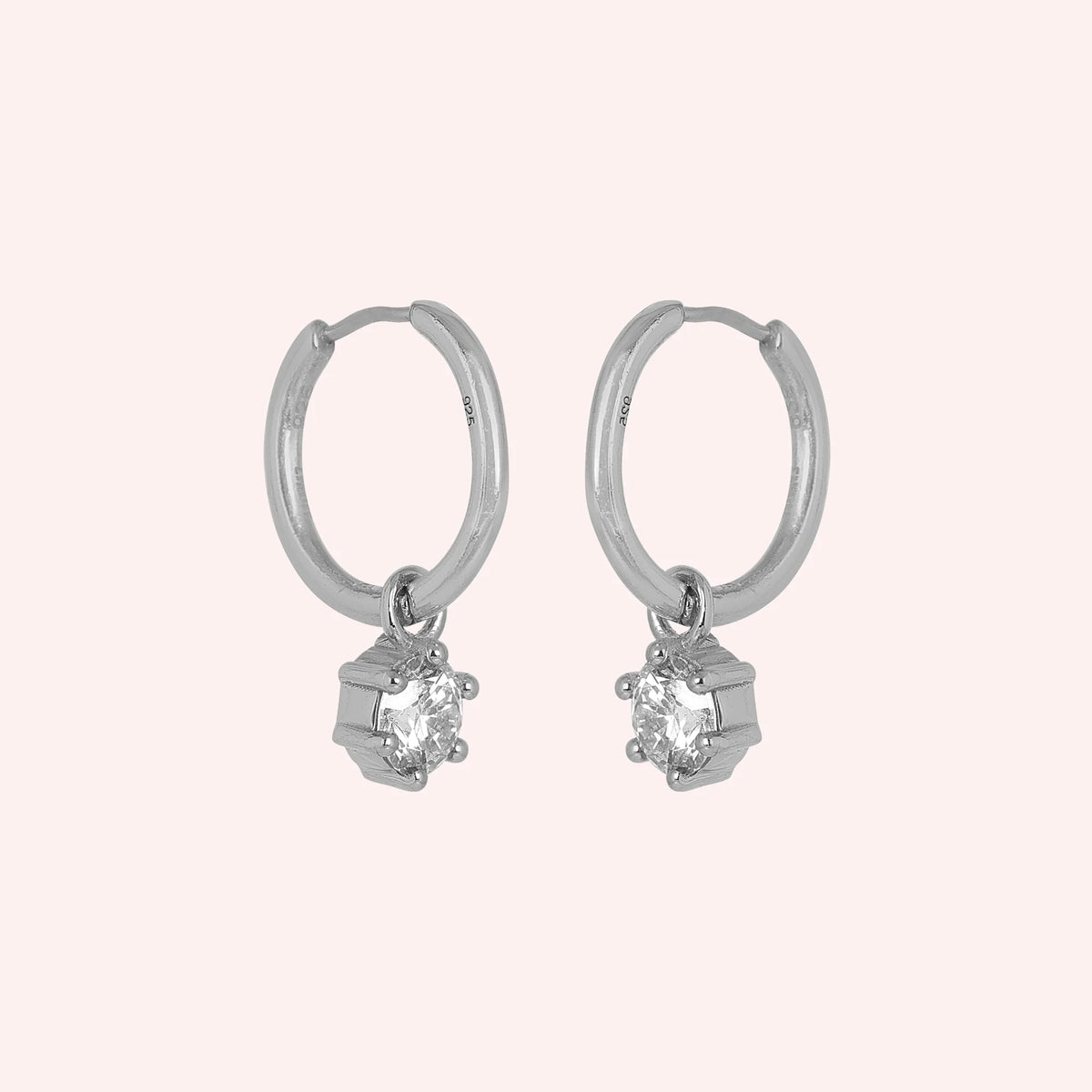 Diamond_earrings_in_sterling_silver_with_a_hoop_drop_design_at_slight_angled_view_on_solid_pink_background