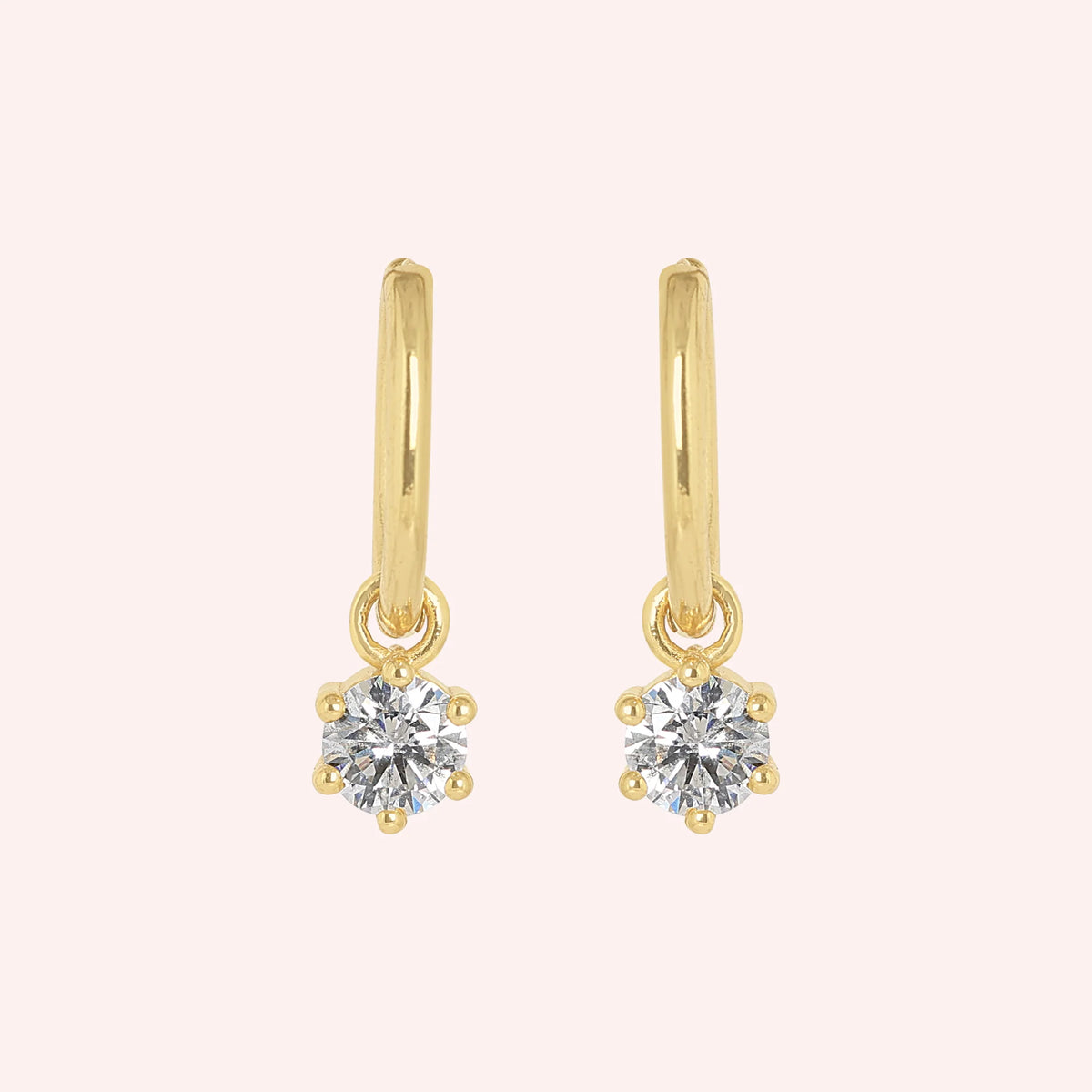 Diamond_earrings_in_gold_plated_silver_with_a_hoop_drop_design_at_front_angle_view_on_solid_pink_background