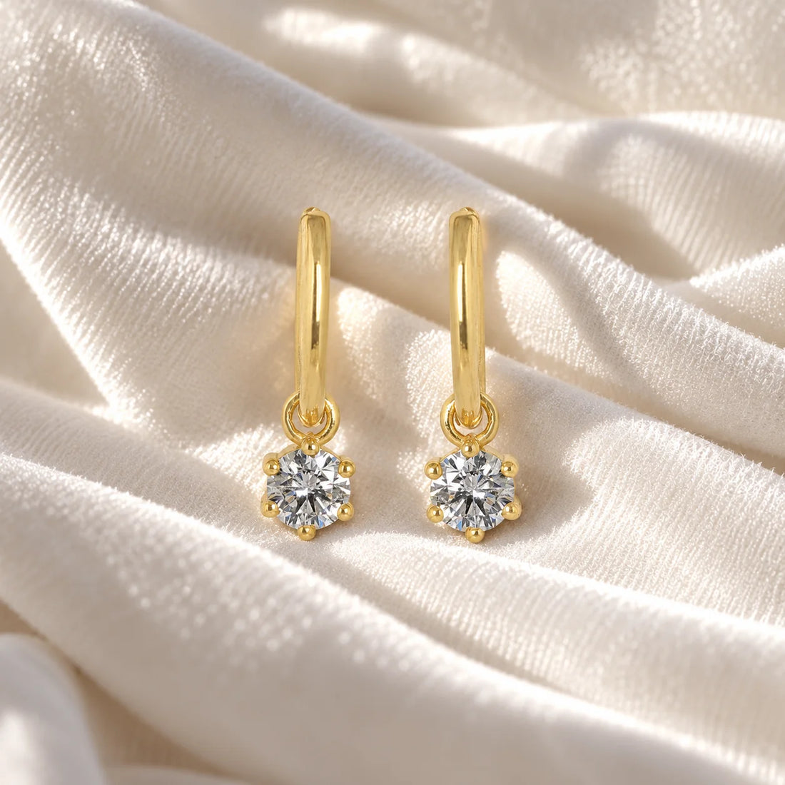Diamond_earrings_in_gold_plated_silver_with_a_hoop_drop_design_at_front_angle_view_on_soft_fabric_background