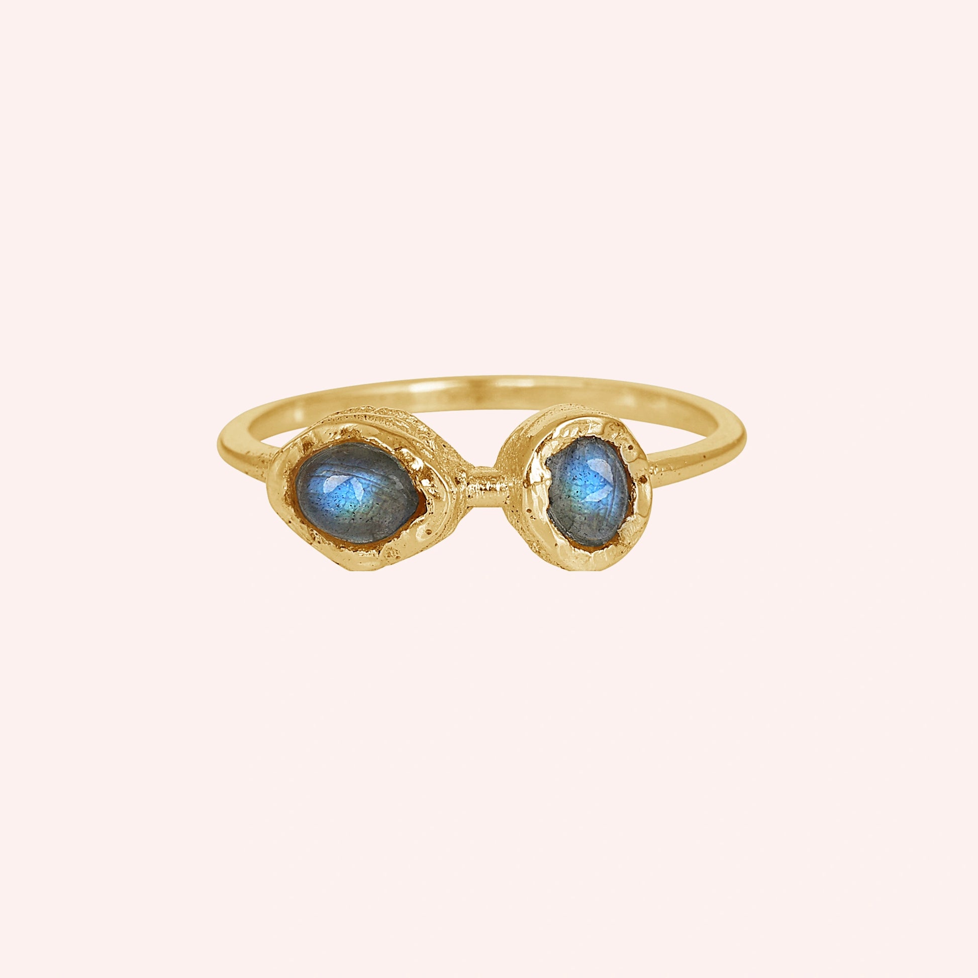 Gold plated double stone ring featuring two oval labradorite gems in rugged setting on a pale pink background straight-on angle