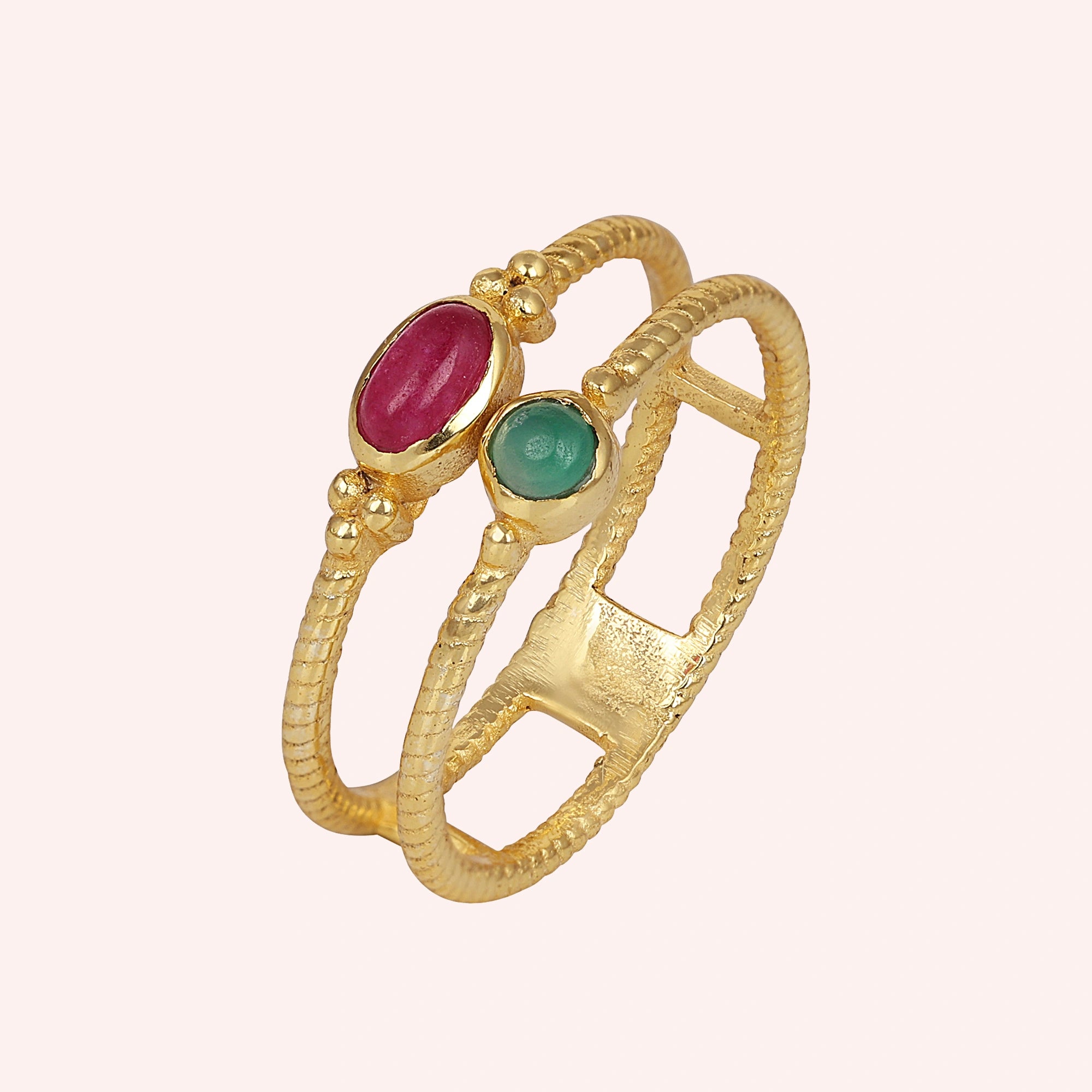 Double_stone_ring_in_gold_plated_silver_in_slightly_angle_with_ruby_and_green_onyx_stones_on_solid_pink_background