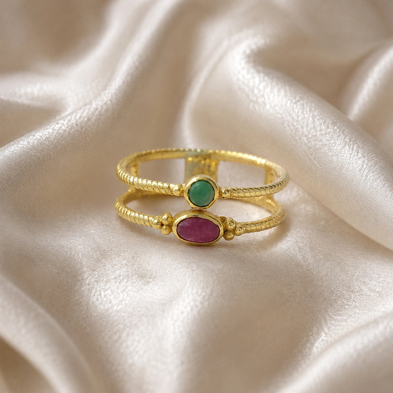Double_stone_ring_in_gold_plated_silver_in_front_angle_with_ruby_and_green_onyx_stones_on_soft_fabric_background