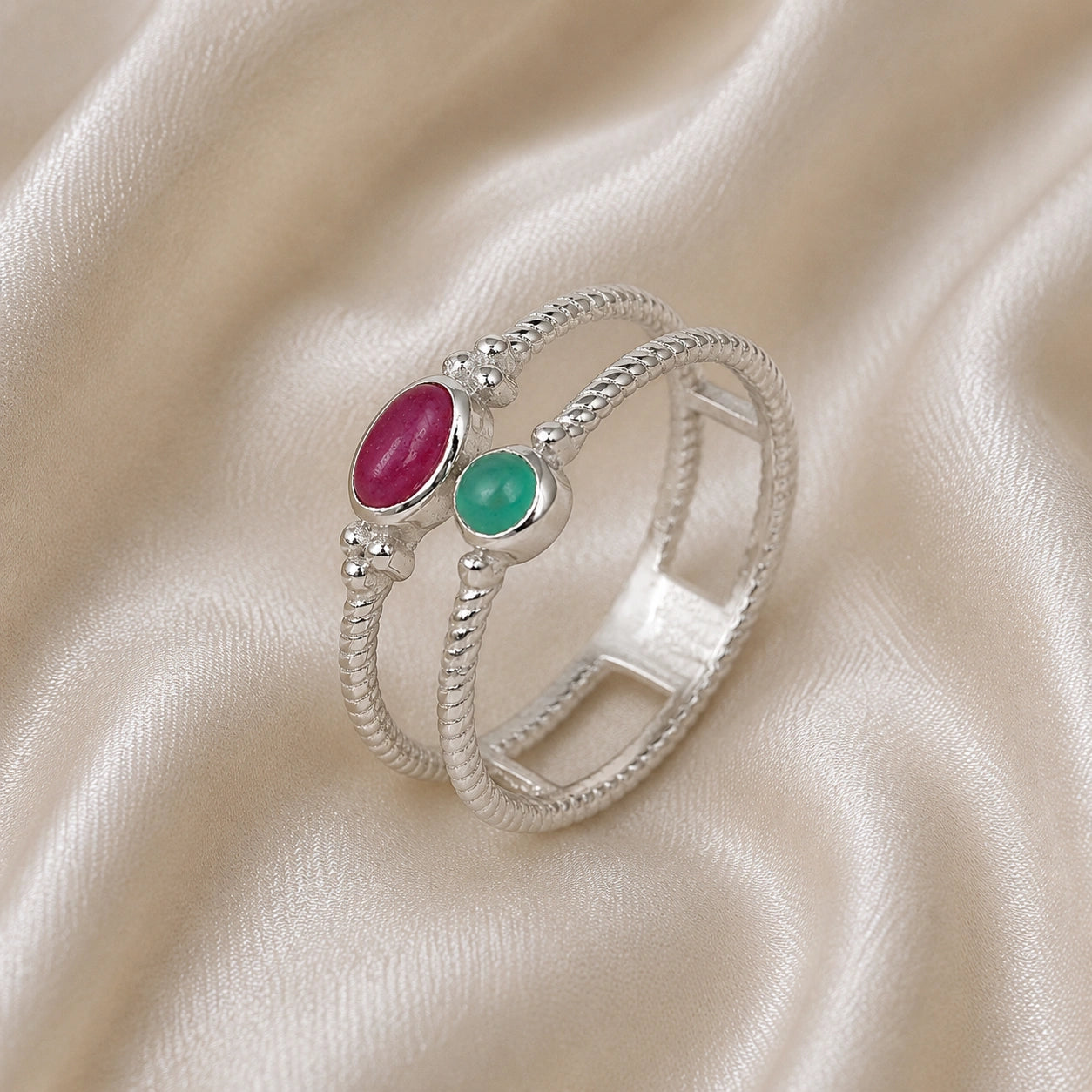 Double_stone_ring_in_sterling_silver_in_slightly_angle_with_ruby_and_green_onyx_stones_on_soft_fabric_background