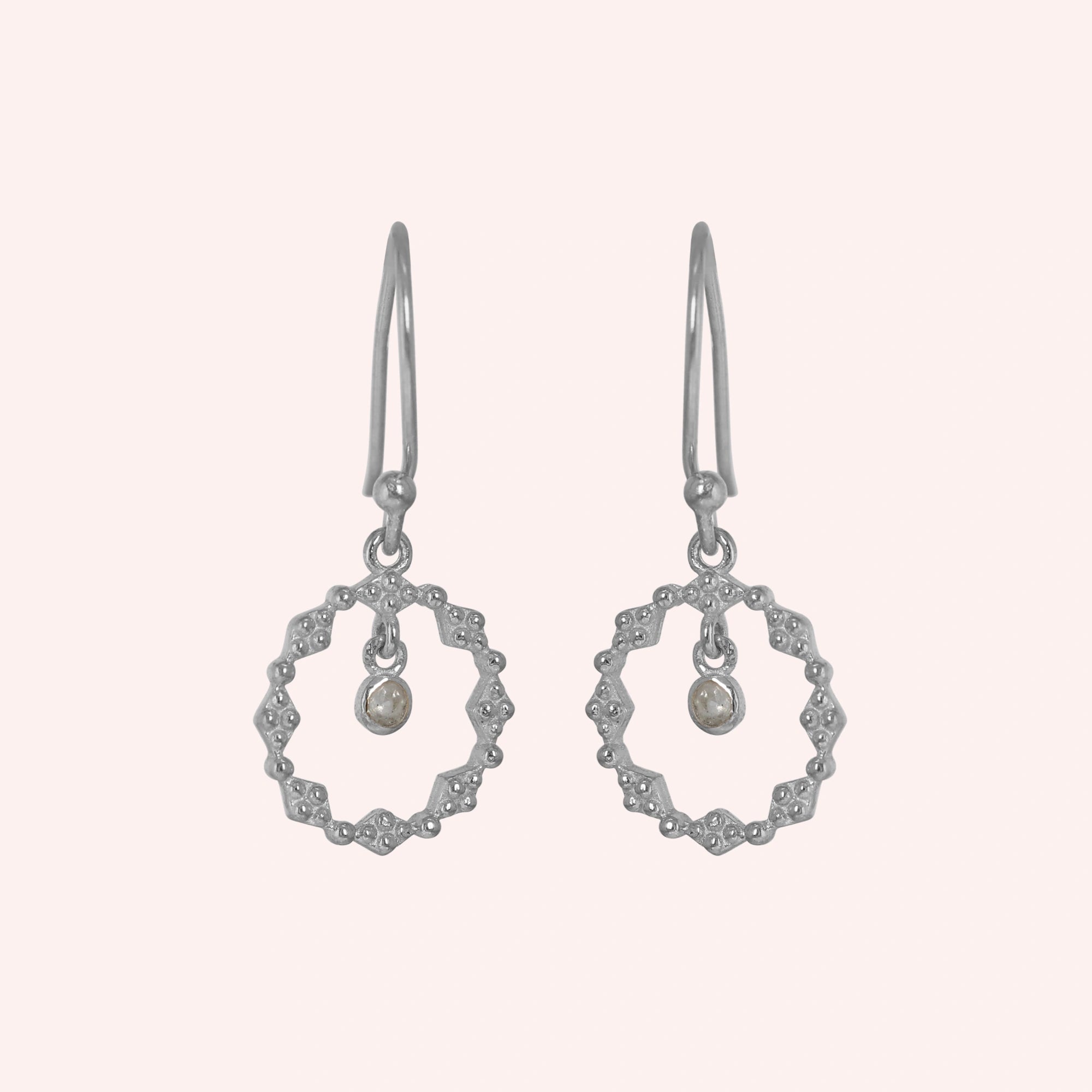 Drop_earrings_sterling_silver_with_textured_design_and_labradorite_stone_in_front_angle_on_solid_pink_background