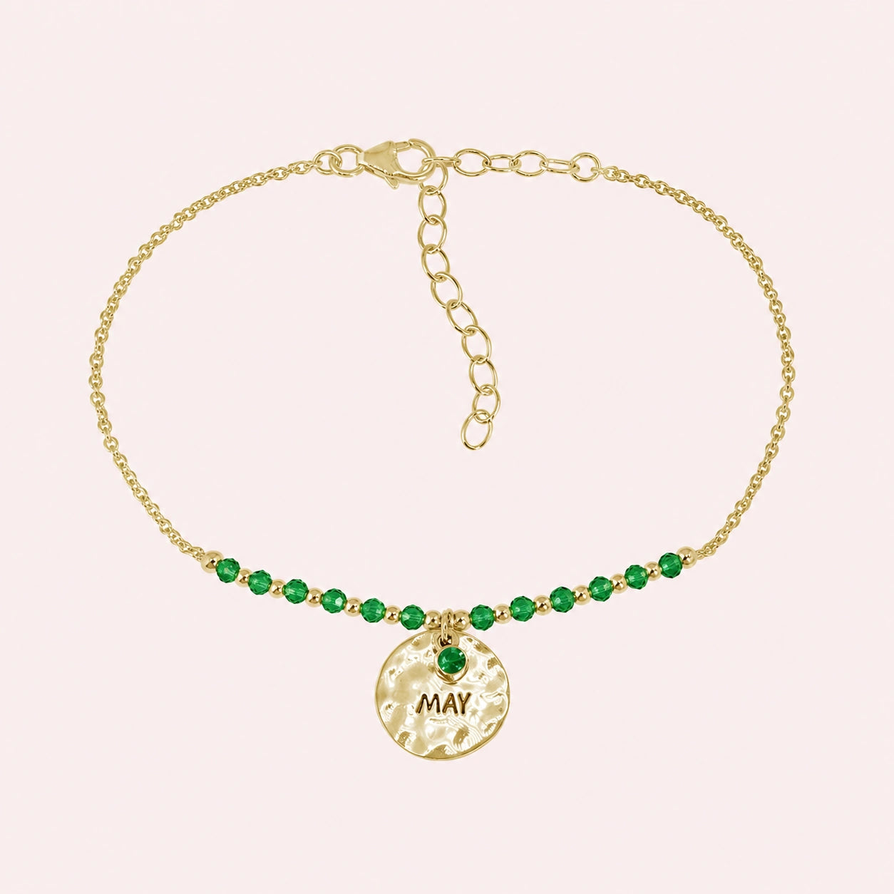 Birthstone_bracelet_in_gold_plated_silver_with_May_charm_and_emerald_beads_on_fine_chain_on_solid_pink_background