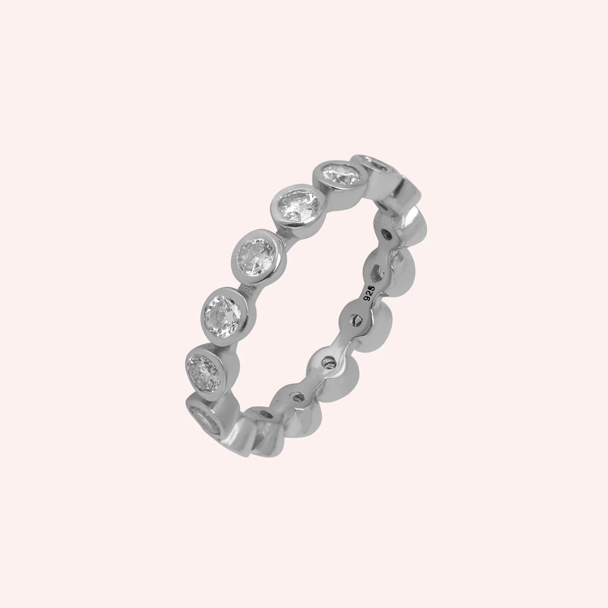 Eternity_ring_in_sterling_silver_with_CZ_stones_at_side_angle_view_on_solid_pink_background