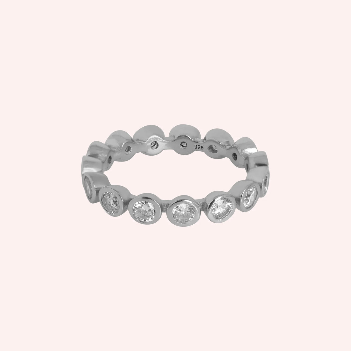 Eternity_ring_in_sterling_silver_with_CZ_stones_at_front_angle_view_on_solid_pink_background