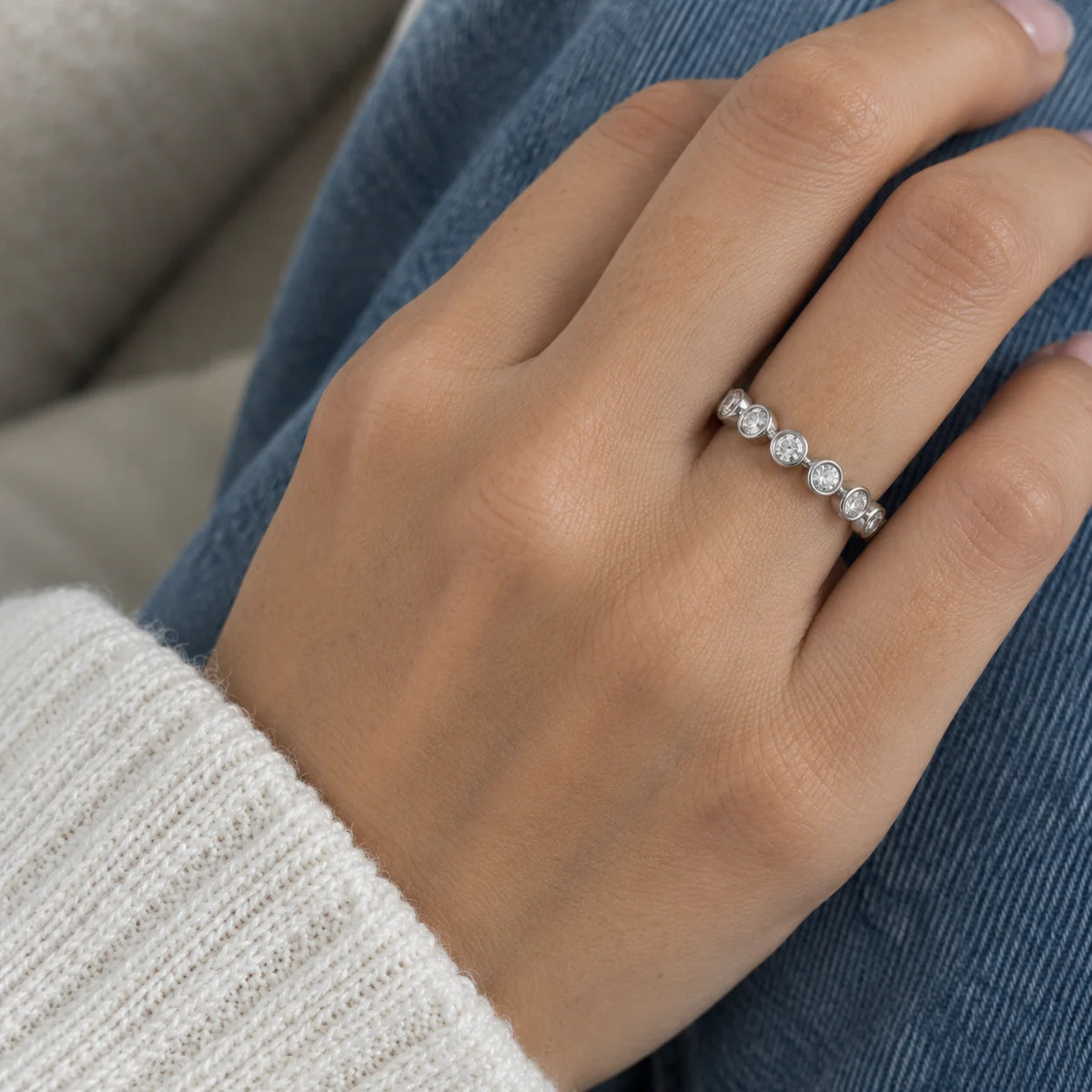 Eternity_ring_in_sterling_silver_with_CZ_stones_at_front_angle_view_worn_by_a_model