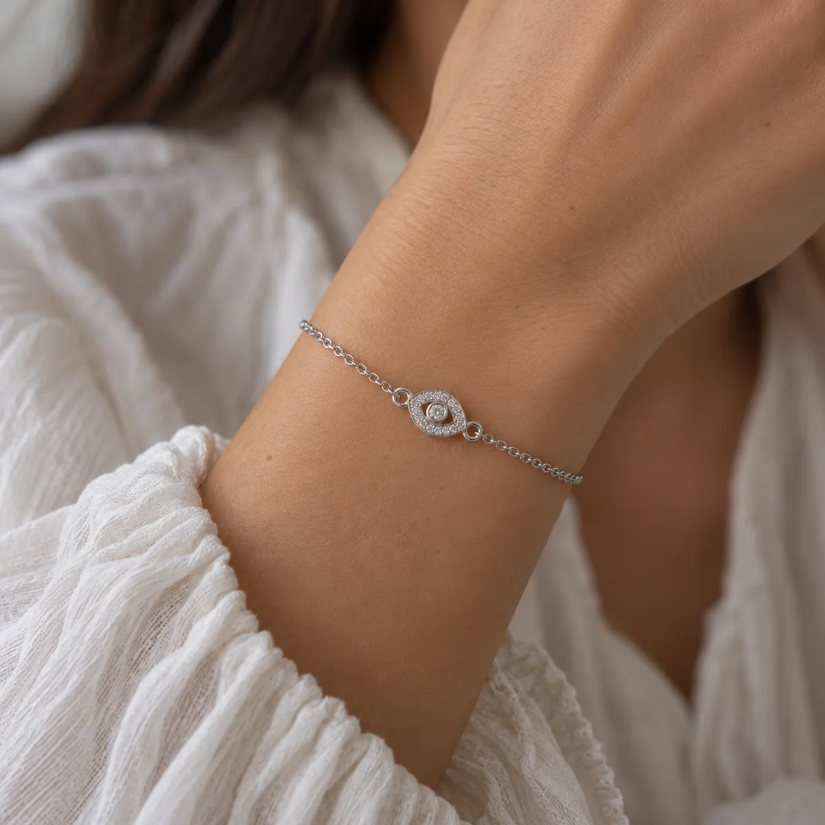 Evil_eye_bracelet_in_sterling_silver_with_CZ_stones_at_front_angle_view_worn_by_a_model