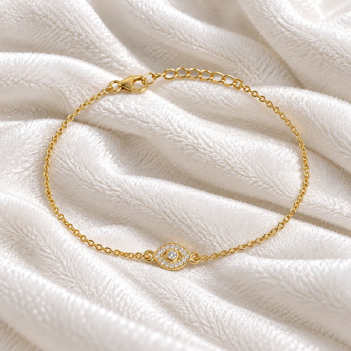 Evil_eye_bracelet_in_gold_plated_silver_with_CZ_stones_at_front_angle_view_on_soft_fabric_background