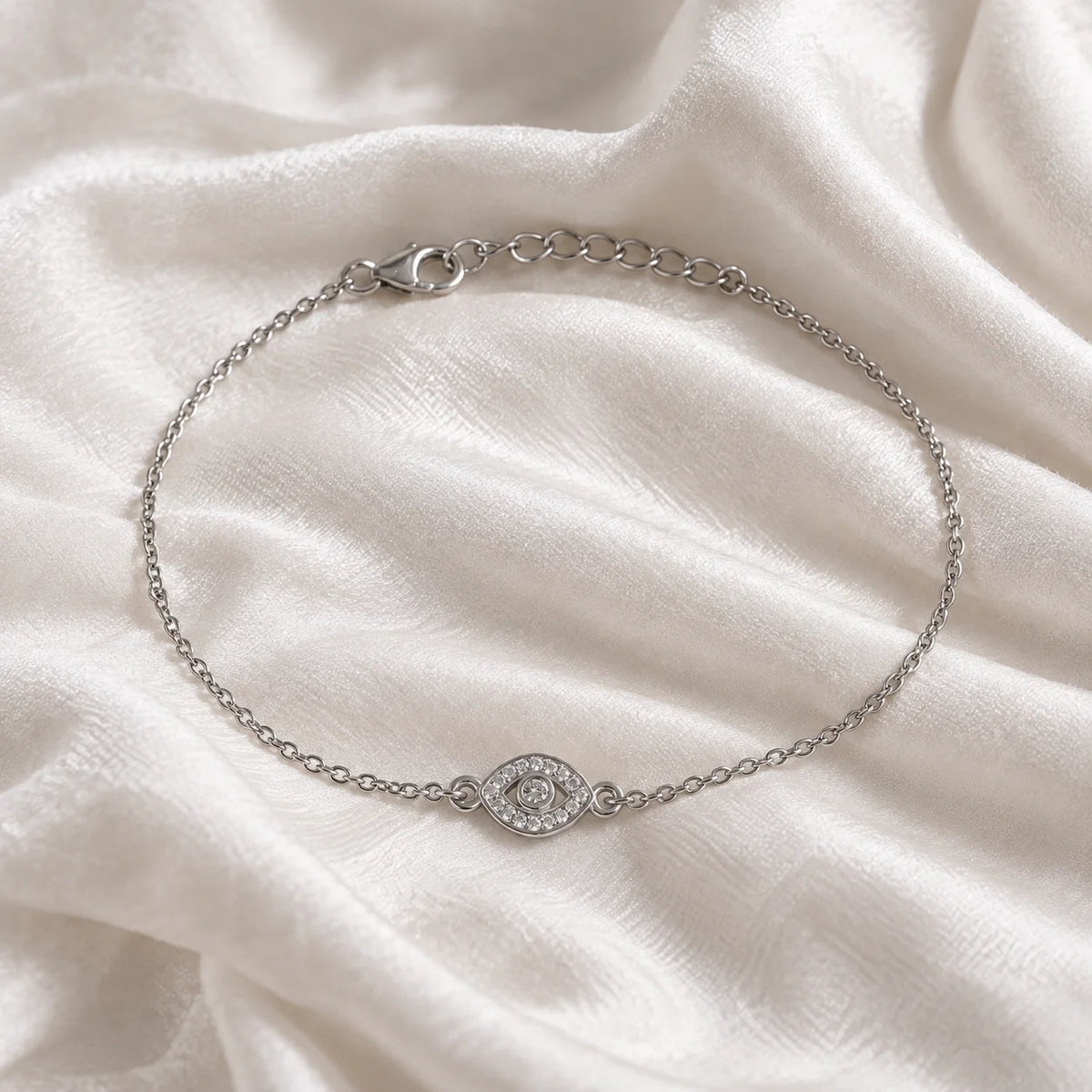 Evil_eye_bracelet_in_sterling_silver_with_lab_grown_diamonds_at_front_angle_view_on_soft_fabric_background