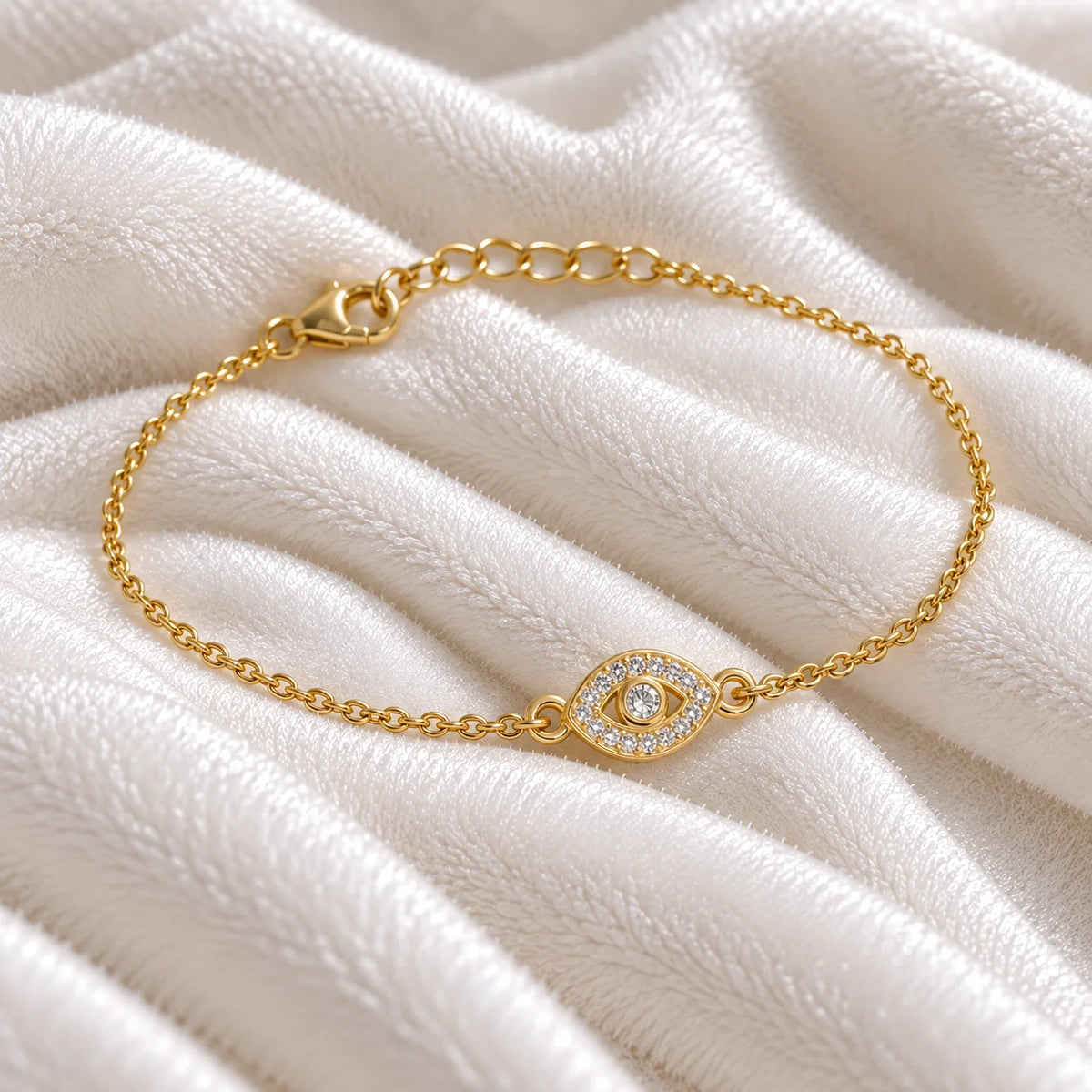 Evil_eye_bracelet_in_gold_plated_silver_with_CZ_stones_at_side_angle_view_on_soft_fabric_background
