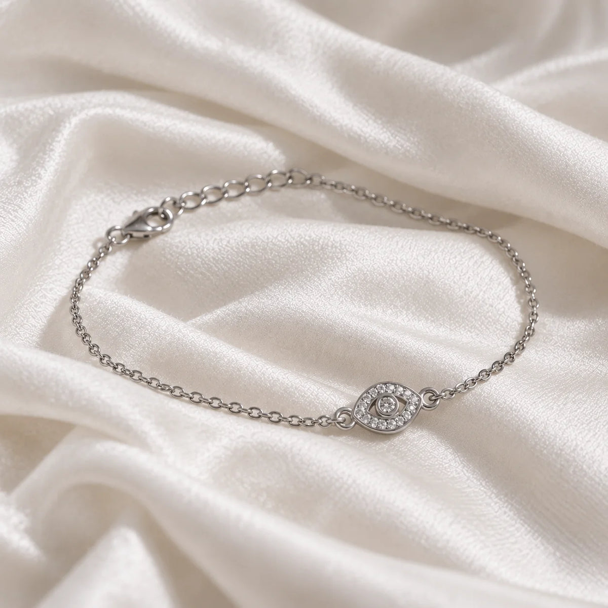 Evil_eye_bracelet_in_slight_silver_with_lab_grown_diamonds_at_slight_angle_view_on_soft_fabric_background
