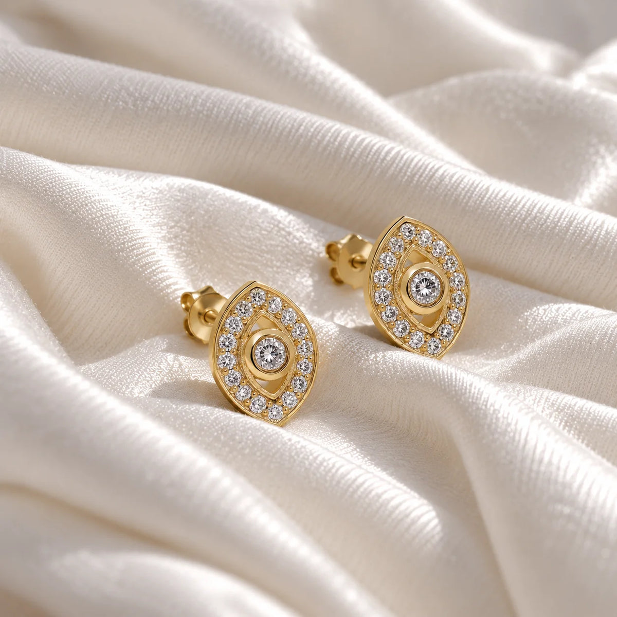 Evil_eye_earrings_in_gold_plated_silver_with_lab_grown_diamonds_at_front_angle_view_on_soft_fabric_background