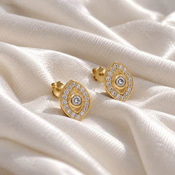 Evil_eye_earrings_in_gold_plated_silver_with_lab_grown_diamonds_at_front_angle_view_on_soft_fabric_background