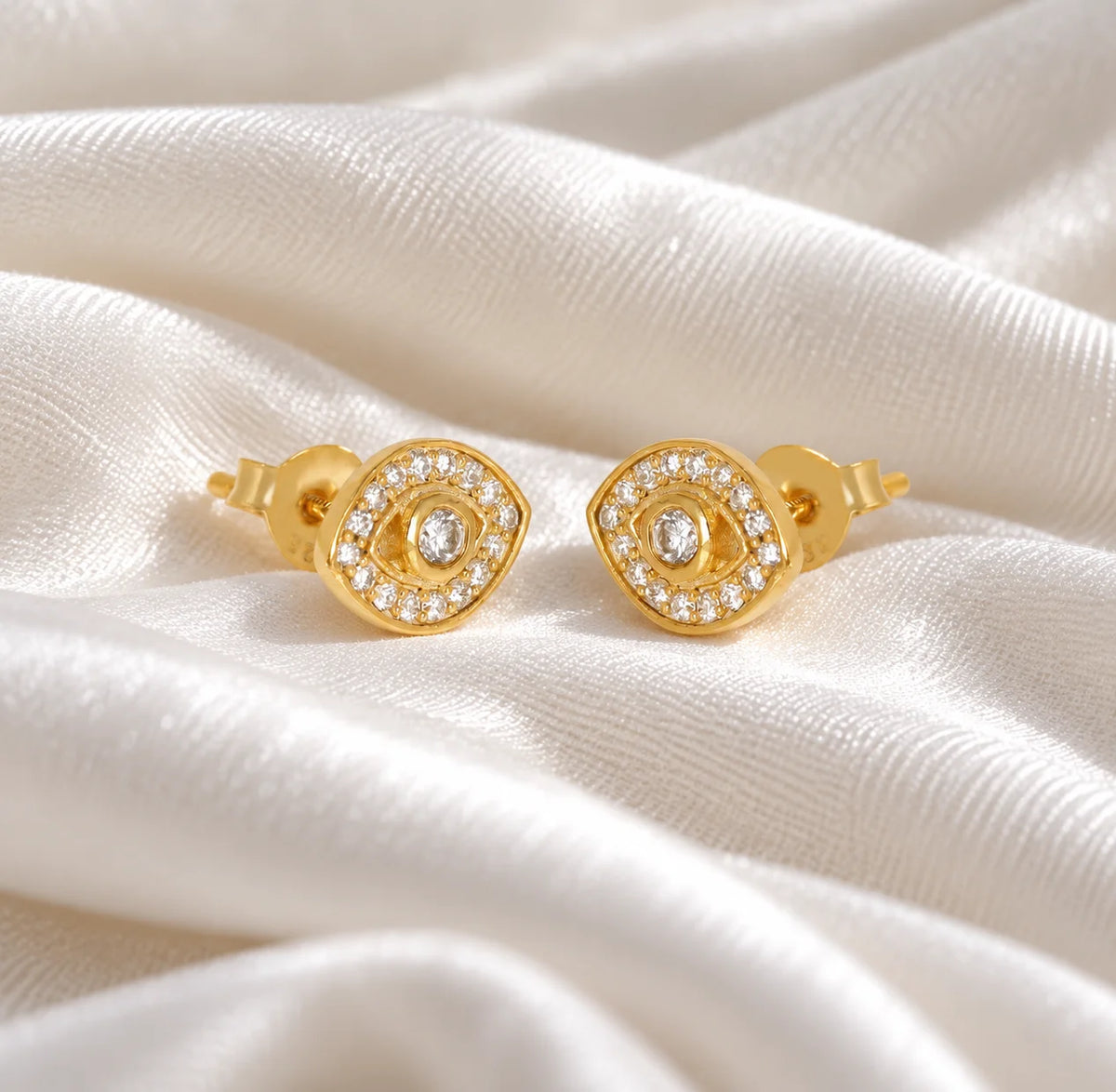 Evil_eye_earrings_in_gold_plated_silver_with_lab_grown_diamonds_at_slight_angle_view_on_soft_fabric_background