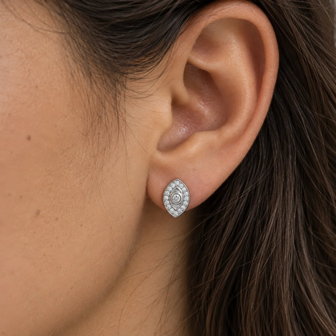 Evil_eye_earrings_in_gold_plated_silver_with_CZ_stones_at_side_angle_view_on_soft_fabric_background