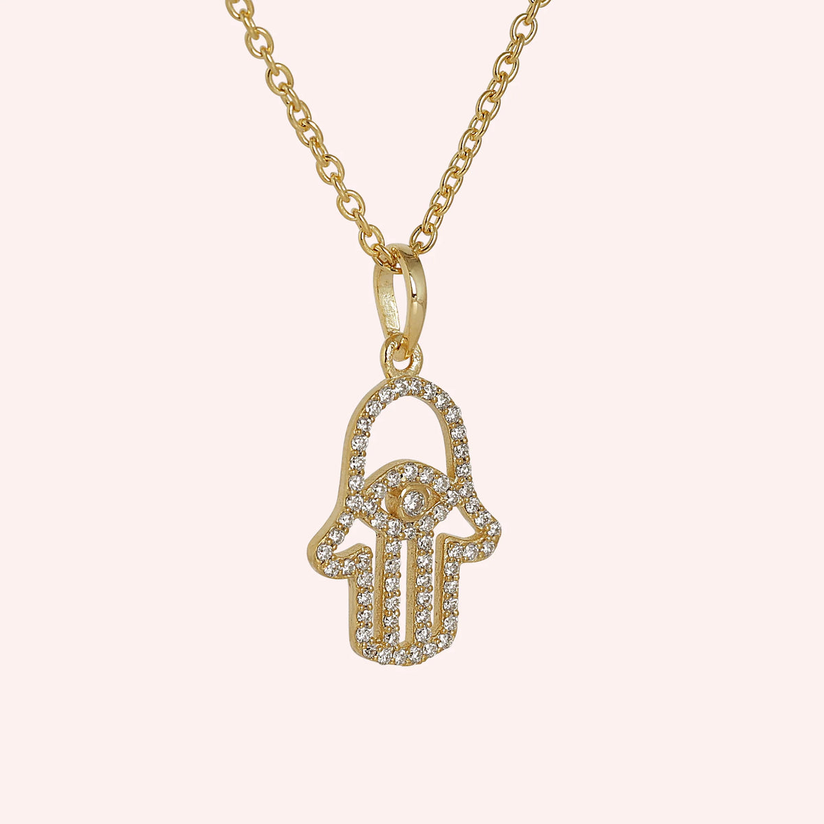 Evil_eye_necklace_in_gold_plated_silver_with_hamsa_hand_design_at_slight_angle_view_on_solid_pink_background