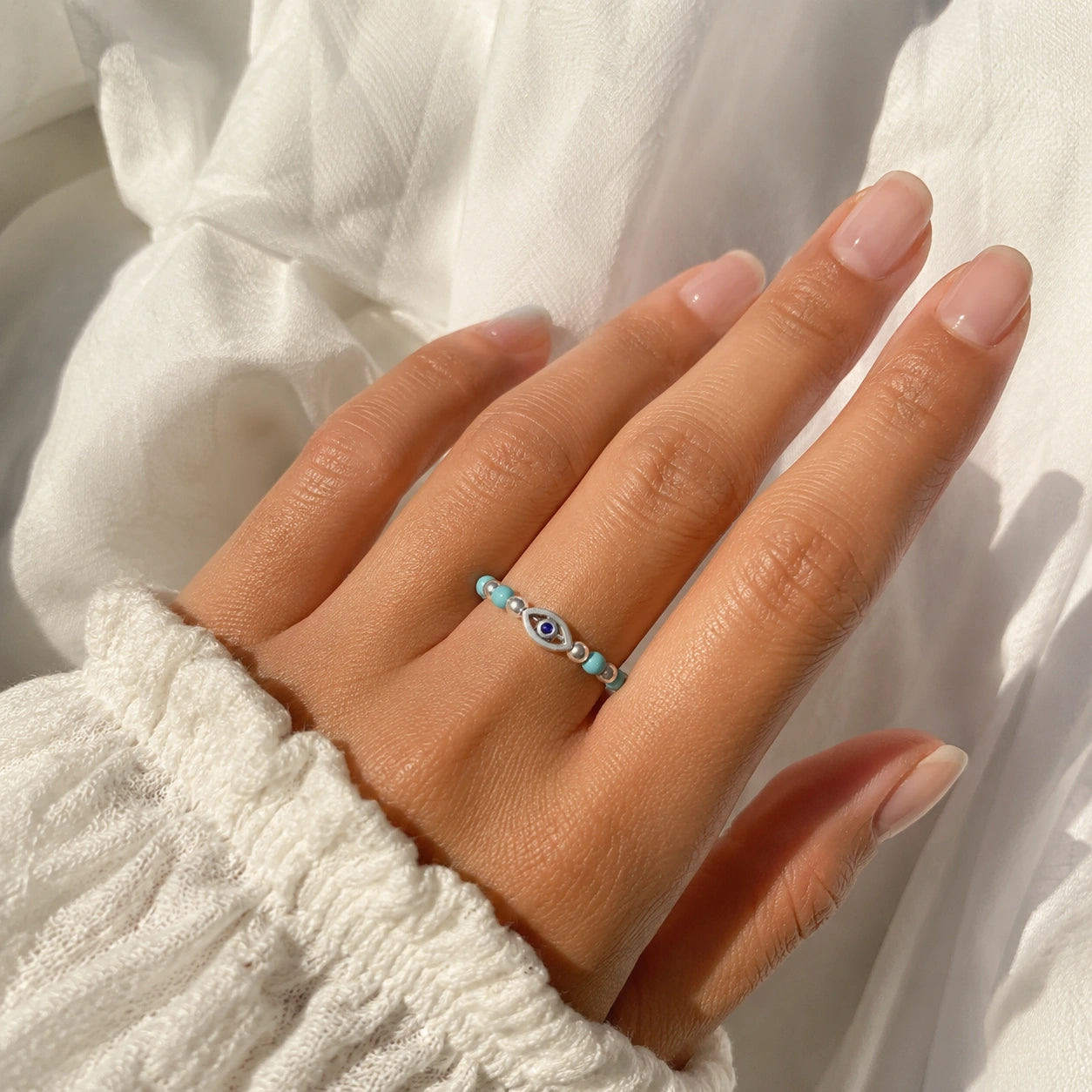 Evil_eye_ring_featuring_turquoise_and_gold_plated_silver_beads_with_blue_iolite_worn_by_a_model