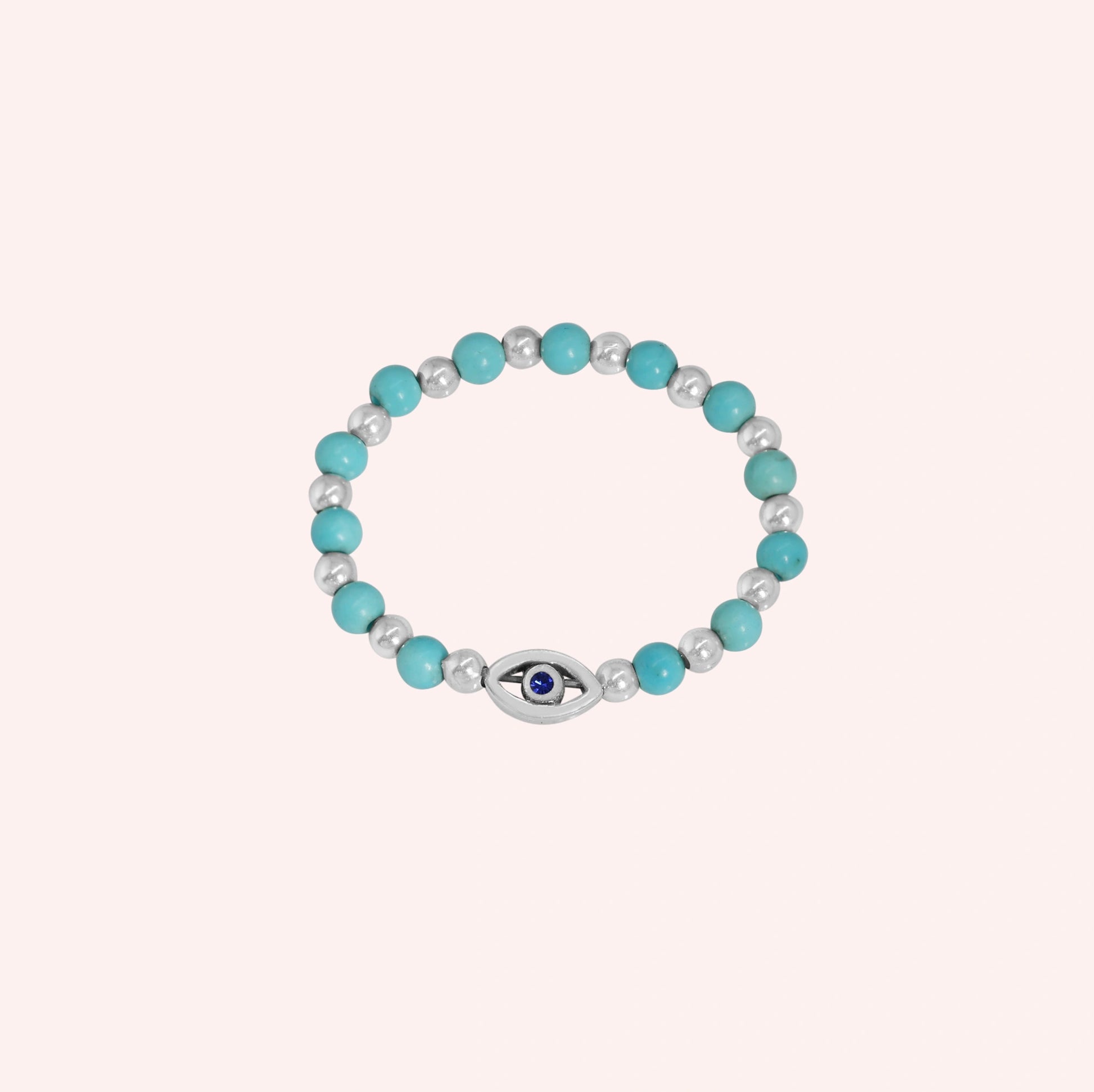Evil_eye_ring_featuring_turquoise_and_sterling_silver_beads_with_blue_iolite_in_front_angle_on_solid_pink_background