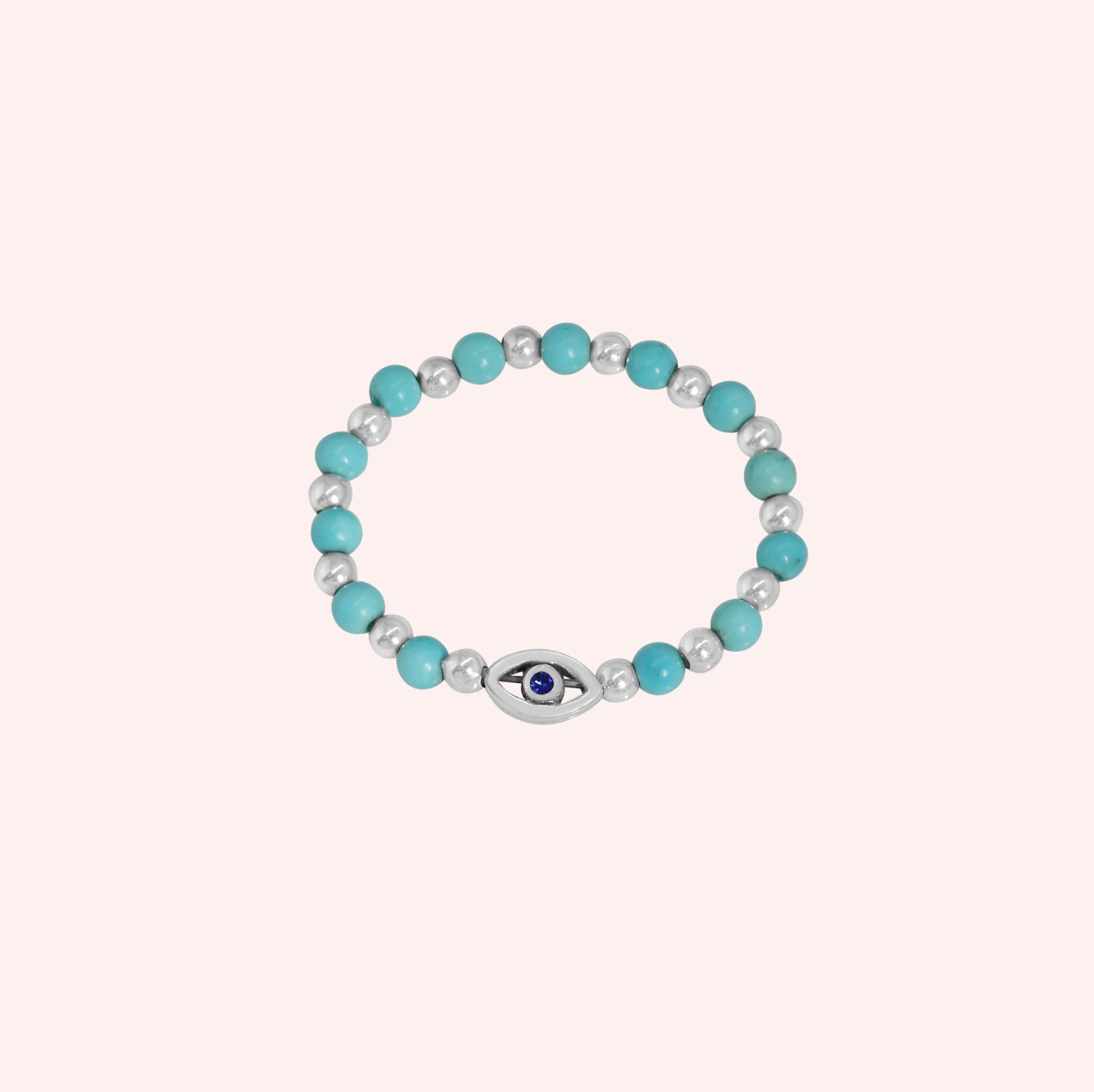 Evil_eye_ring_featuring_turquoise_and_sterling_silver_beads_with_blue_iolite_in_front_angle_on_solid_pink_background
