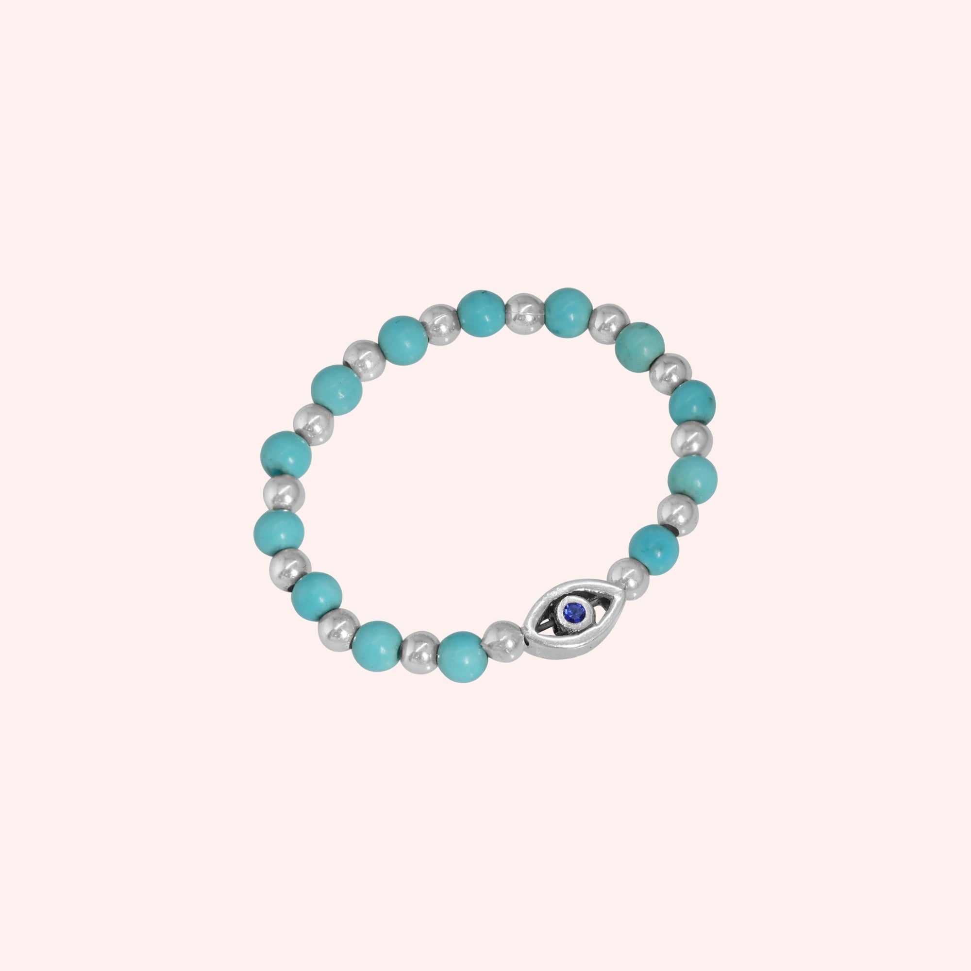 Evil_eye_ring_featuring_turquoise_and_sterling_silver_beads_with_blue_iolite_in_slightly_angled_on_solid_pink_background