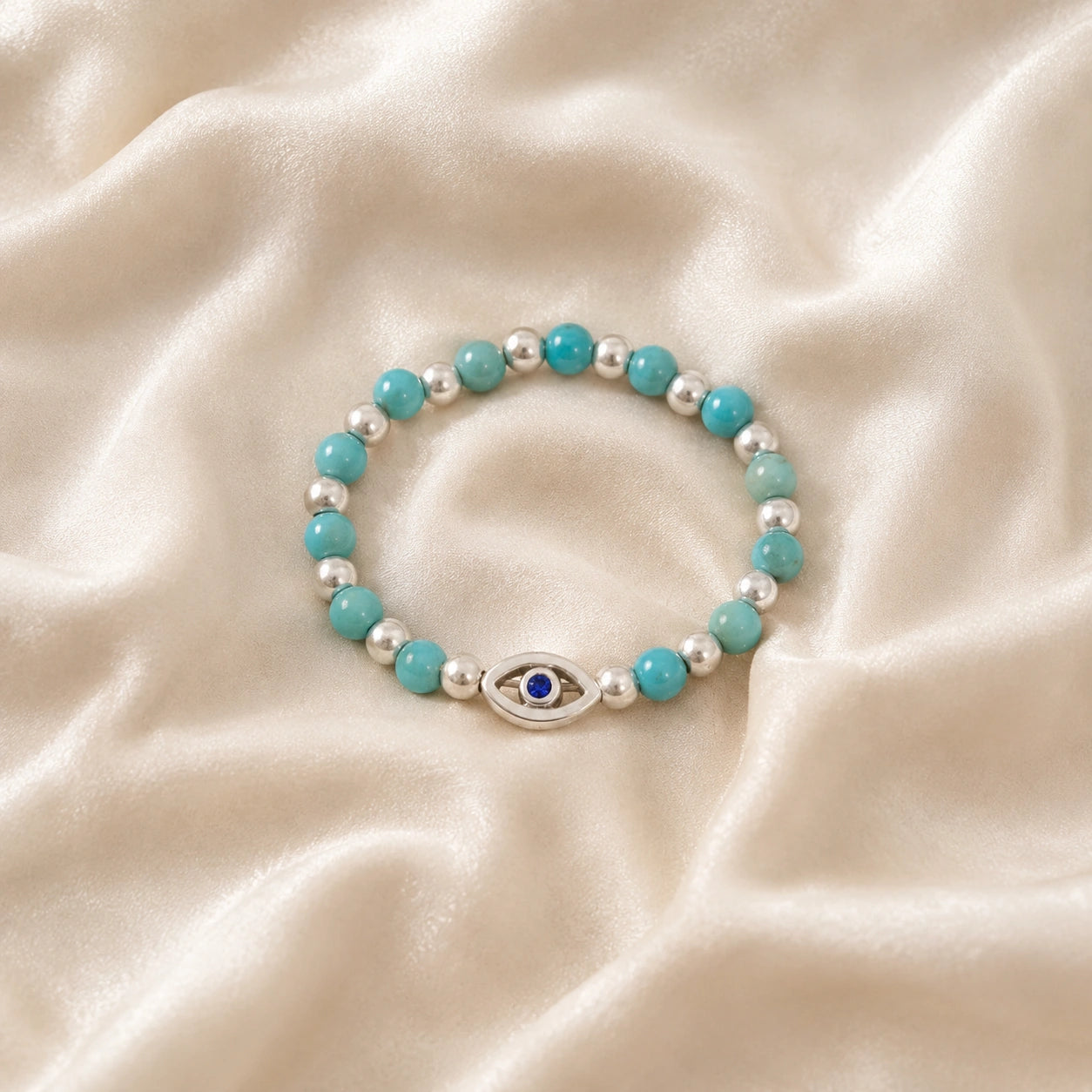 Evil_eye_ring_featuring_turquoise_and_sterling_silver_beads_with_blue_iolite_in_front_angle_on_soft_fabric_background