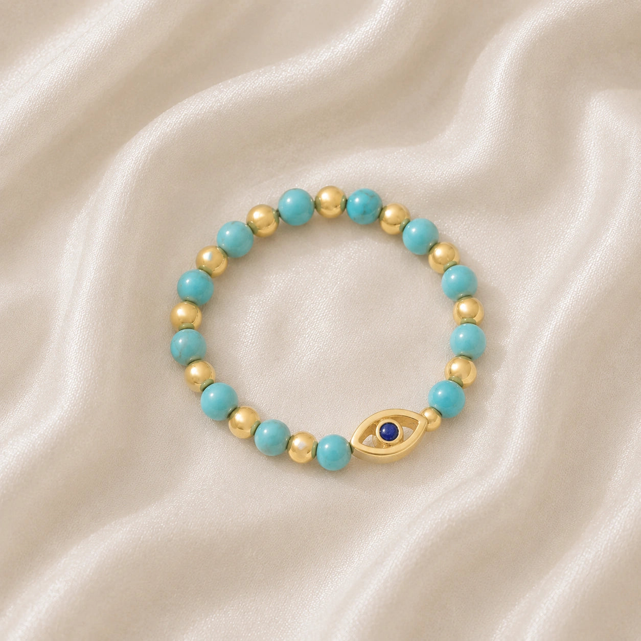 Evil_eye_ring_featuring_turquoise_and_gold_plated_silver_beads_with_blue_iolite_in_slightly_angled_on_soft_fabric_background