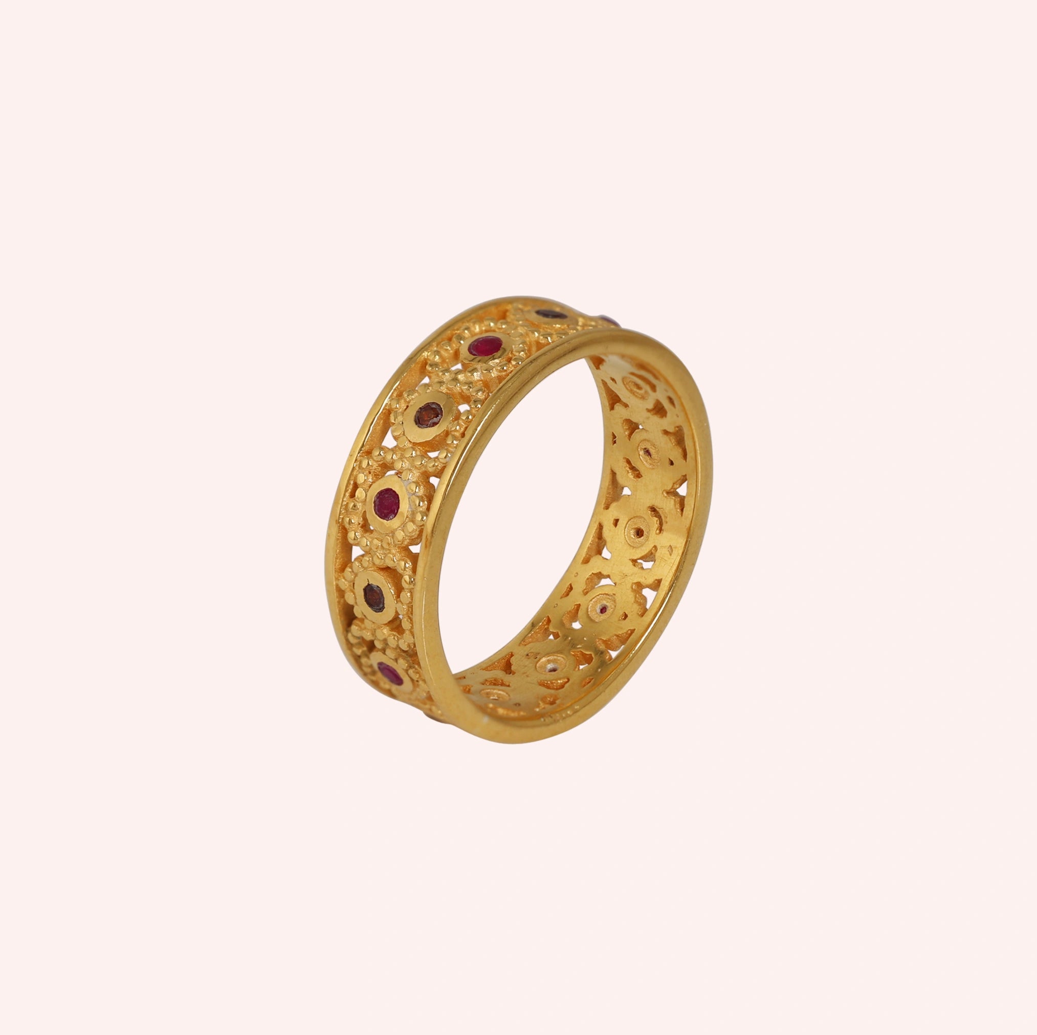Filigree-ring-with-ruby-and-garnet-stones-gold-plated-silver-angled-view-on-soft-pink-background