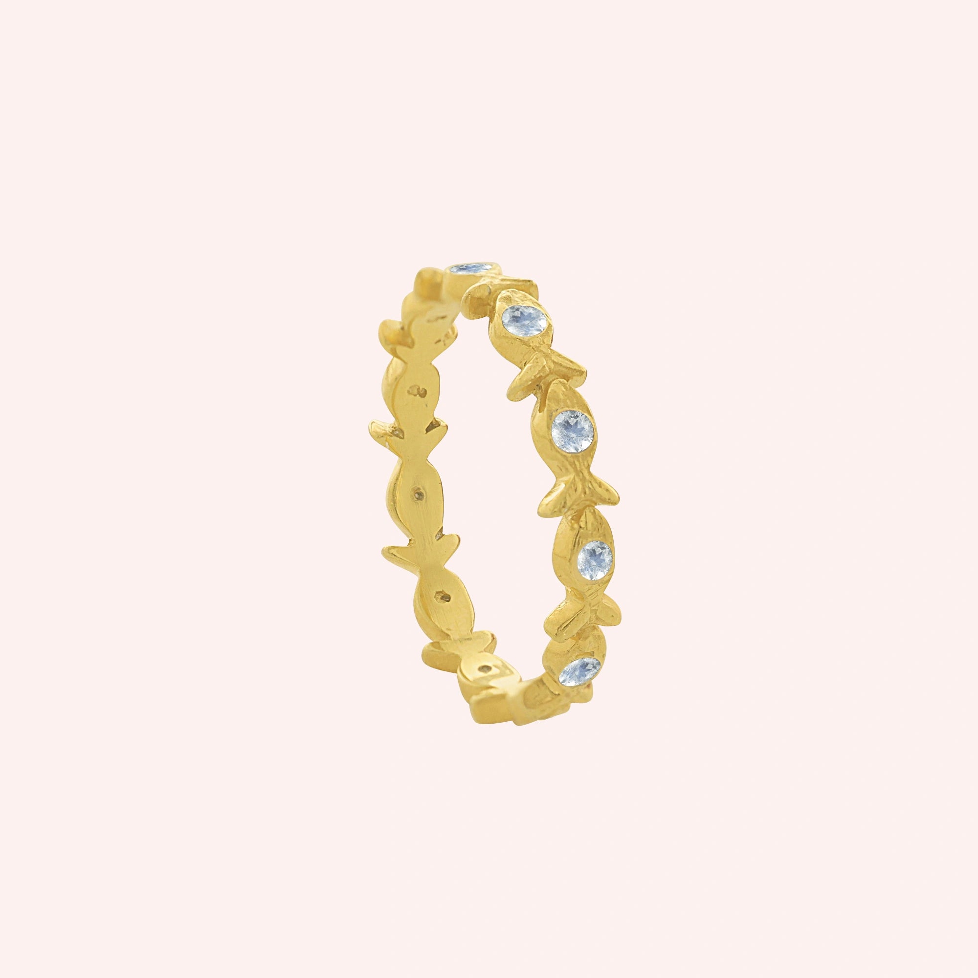 Fish_ring_gold_plated_silver_moonstone_eternity_band_in_side_angle_view_on_solid_pink_background